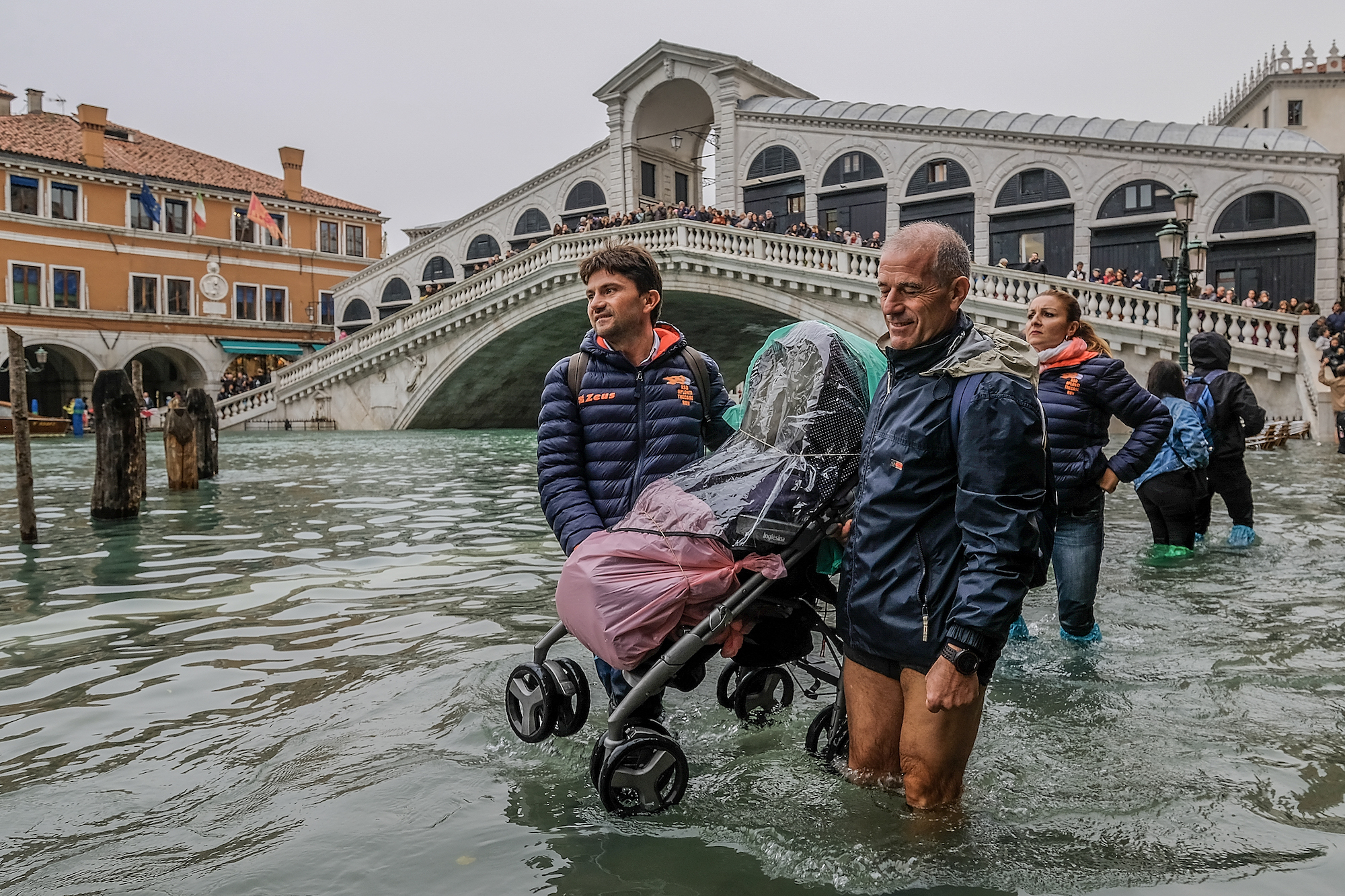 two men hold a pram in Venice in the 2019 floods