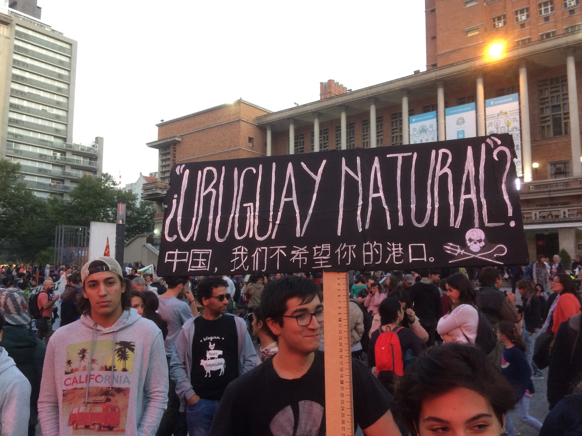 A young man holds up a banner reading "Uruguay natural?" at a protest.