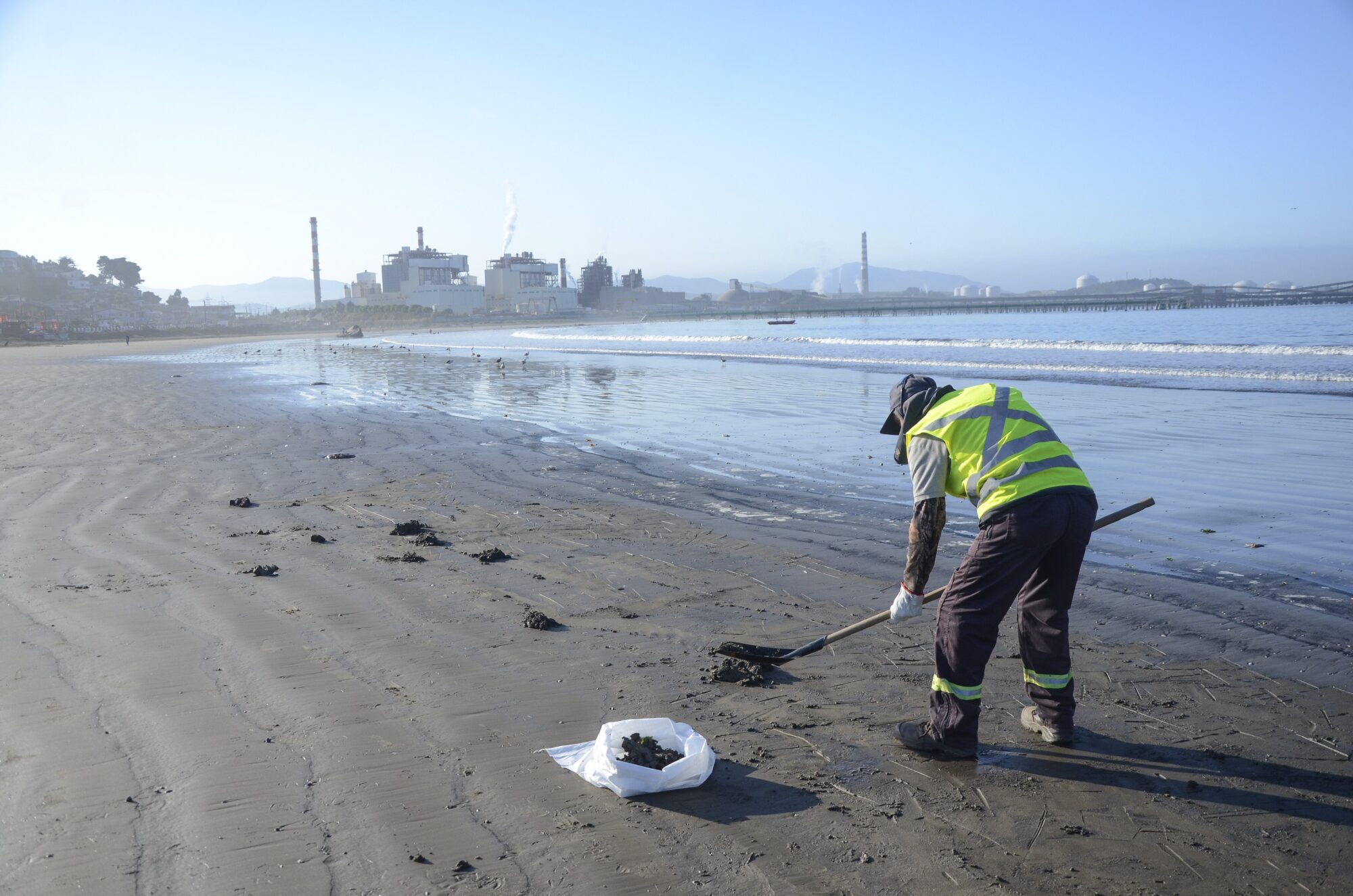 <p>A clean-up crew called in by AES Gener, owner of the coal-fired power plants operating in Quintero and Puchuncaví, regularly cleans the coal from the beach (Image: Saul Mansilla)</p>