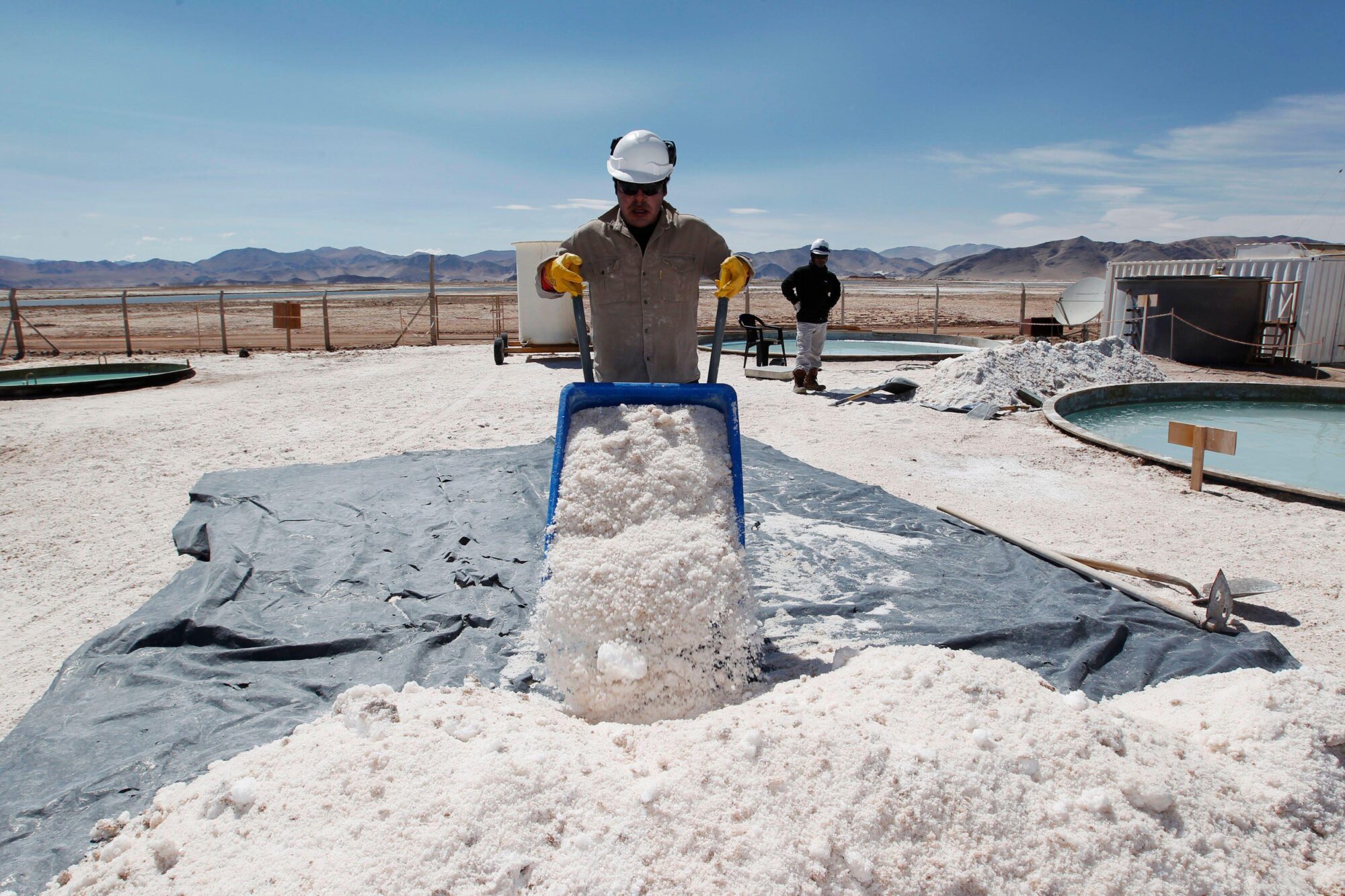 A worker with a wheelbarrow full of salt in a lithium deposit.