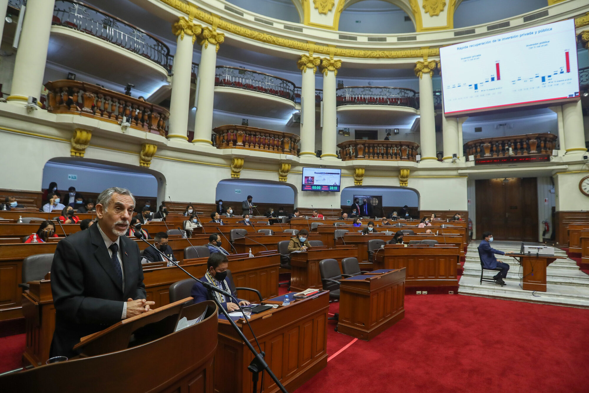 A man in a suit and tie speaks in front of a microphone in the Peruvian Congress.