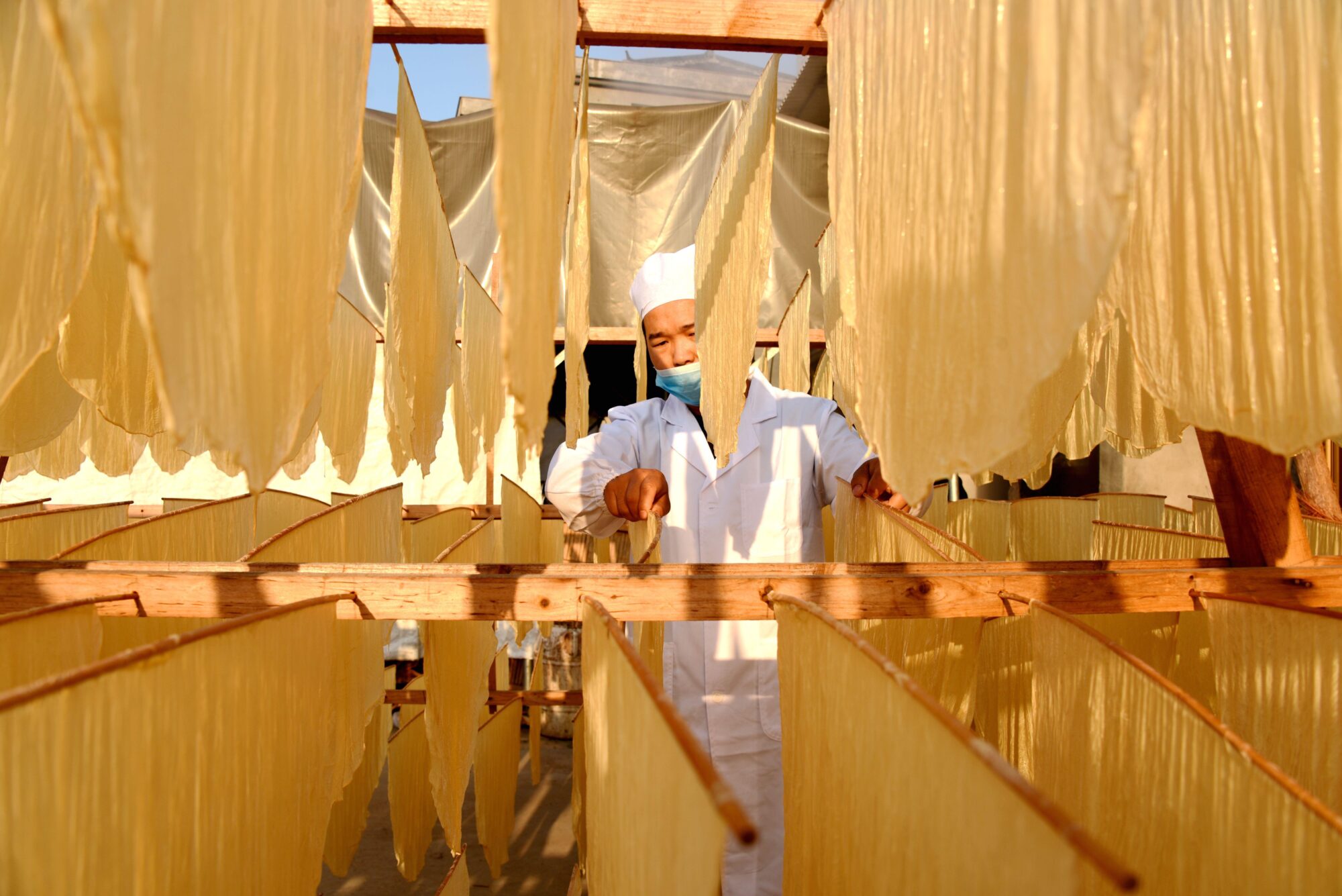 Una persona seca piel de tofu en una cabaña de secado
