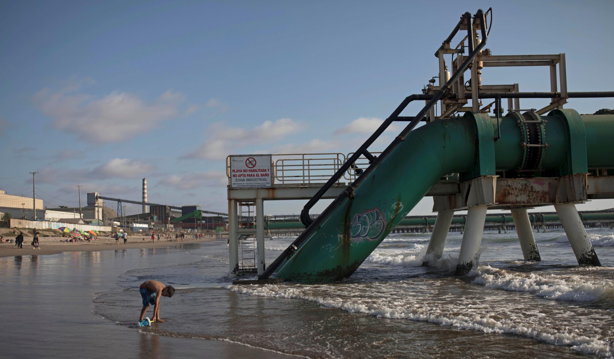 A child plays on the beach in front of a thermoelectric plant pipeline at Las Ventanas in Valparaiso, Chile