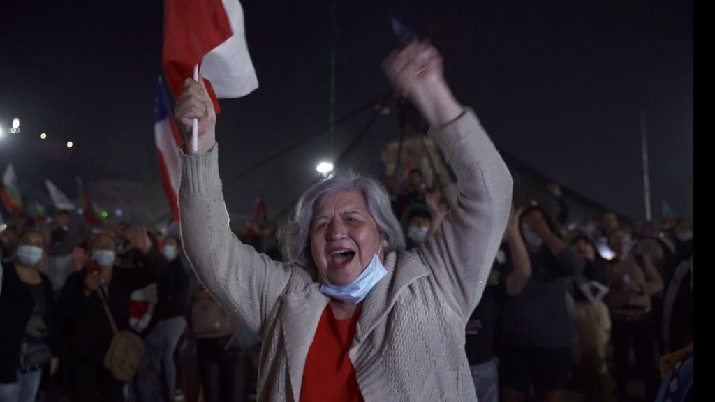 Uma mulher comemora na rua com a bandeira chilena na mão.