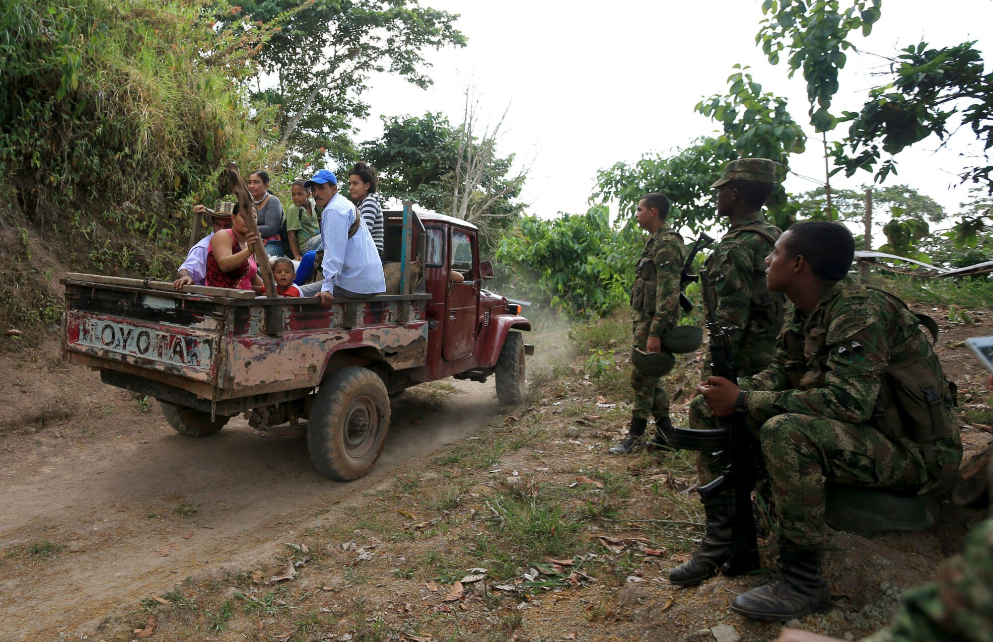 People in a pick-up truck and military on the road