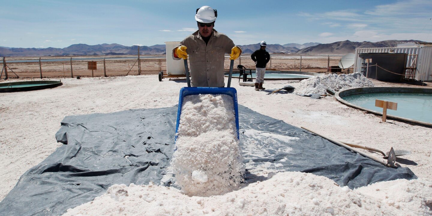 Um trabalhador com um carrinho de mão cheio de sal em um depósito de lítio.