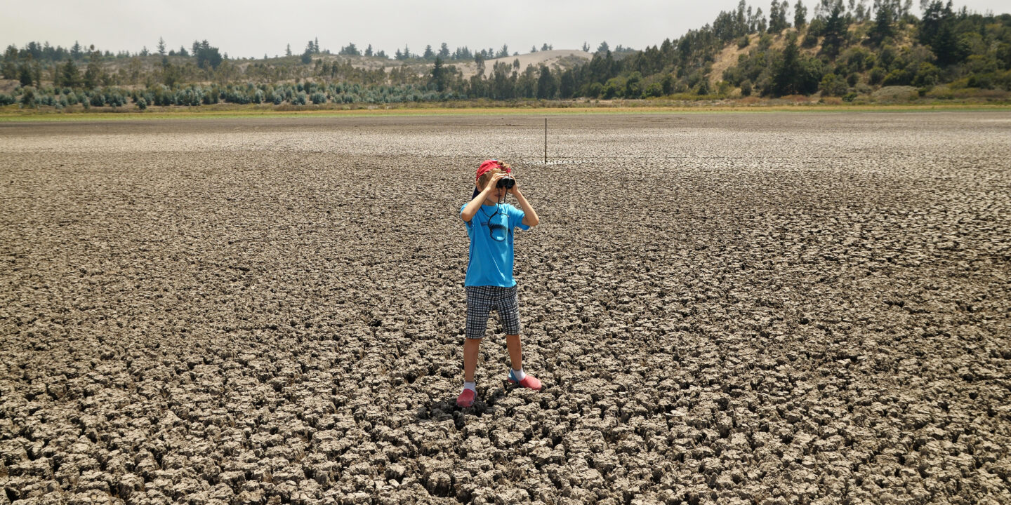 Um menino com binóculos no meio de um deserto no Chile