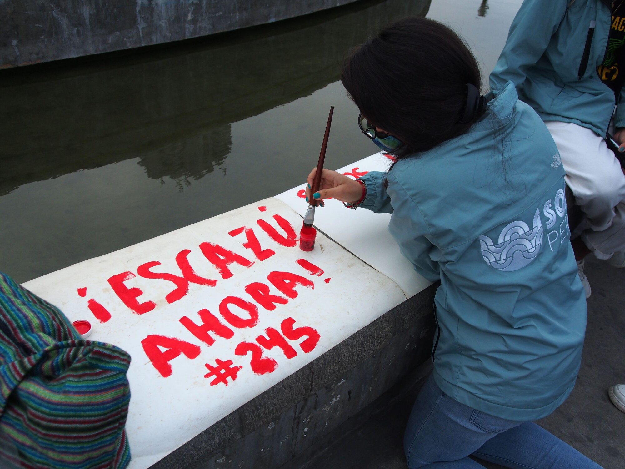 A person paints a sign saying "Escazú now!
