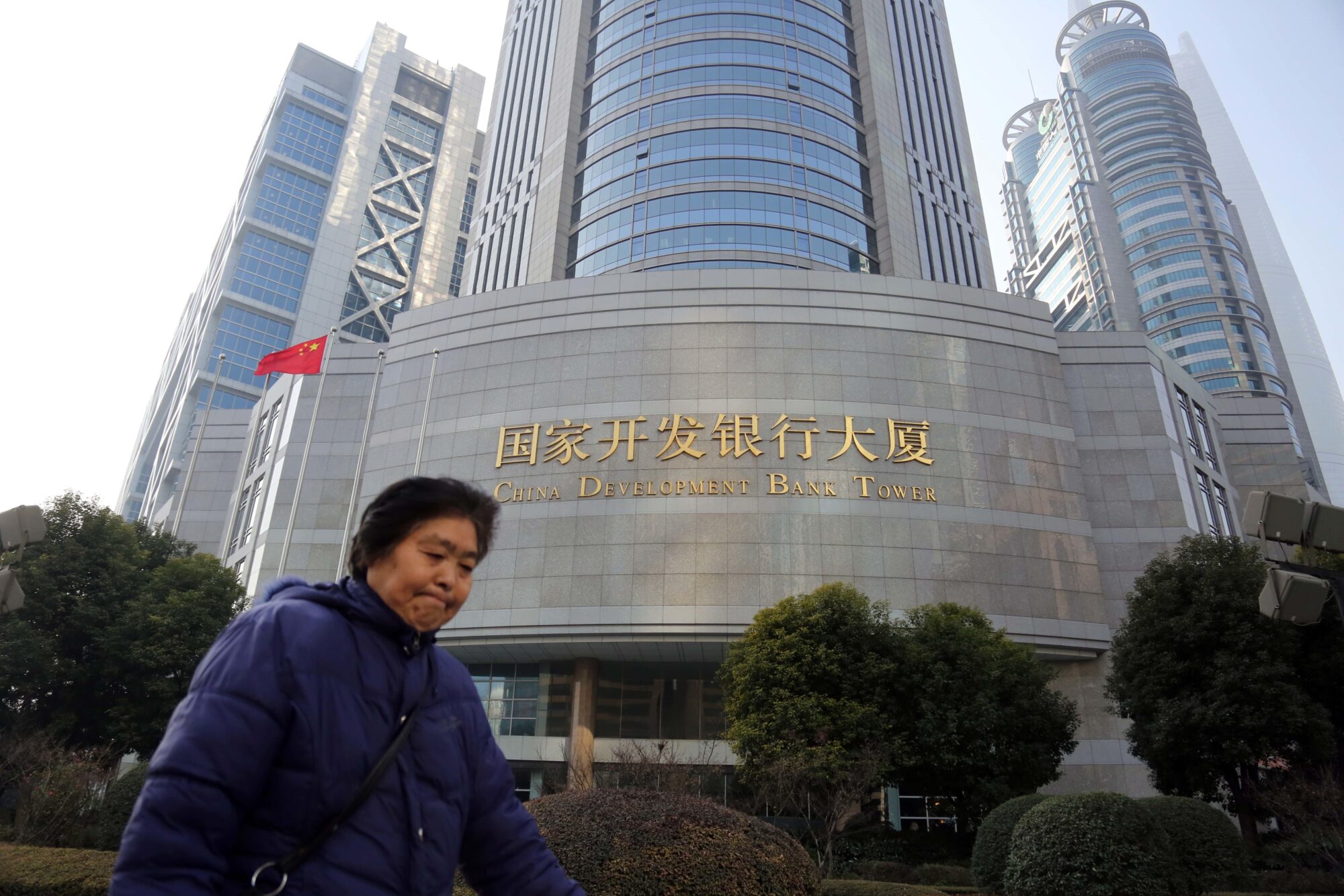 Uma mulher caminhando em frente ao prédio do China Development Bank.