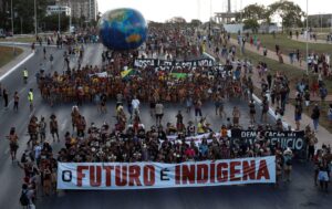 <p>Indígenas protestam contra o presidente Jair Bolsonaro e pela demarcação das terras indígenas, em Brasília, em abril de 2022. O grupo carrega uma faixa com os dizeres &#8216;O futuro é indígena&#8217; (Imagem: Adriano Machado / Alamy)</p>