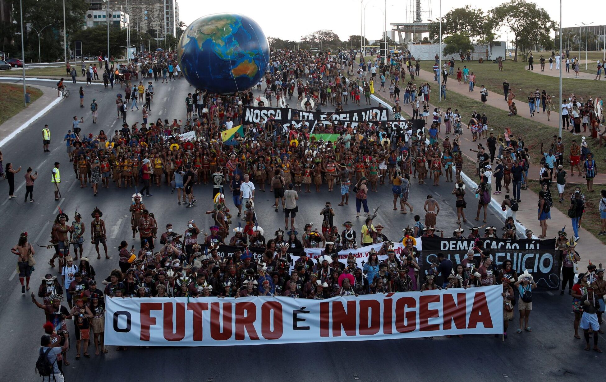 <p>Indigenous people protest against Brazilian president Jair Bolsonaro and in favour of the demarcation of indigenous lands, in Brasília, April 2022. The group carries a banner with the words ‘The future is indigenous’ (Image: Adriano Machado / Alamy)</p>