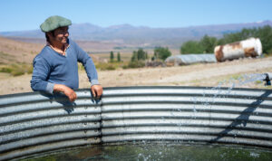 Un agricultor con una boina apoyado en una pileta llena de agua