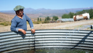 A farmer in a beret leaning on a basin full of water.