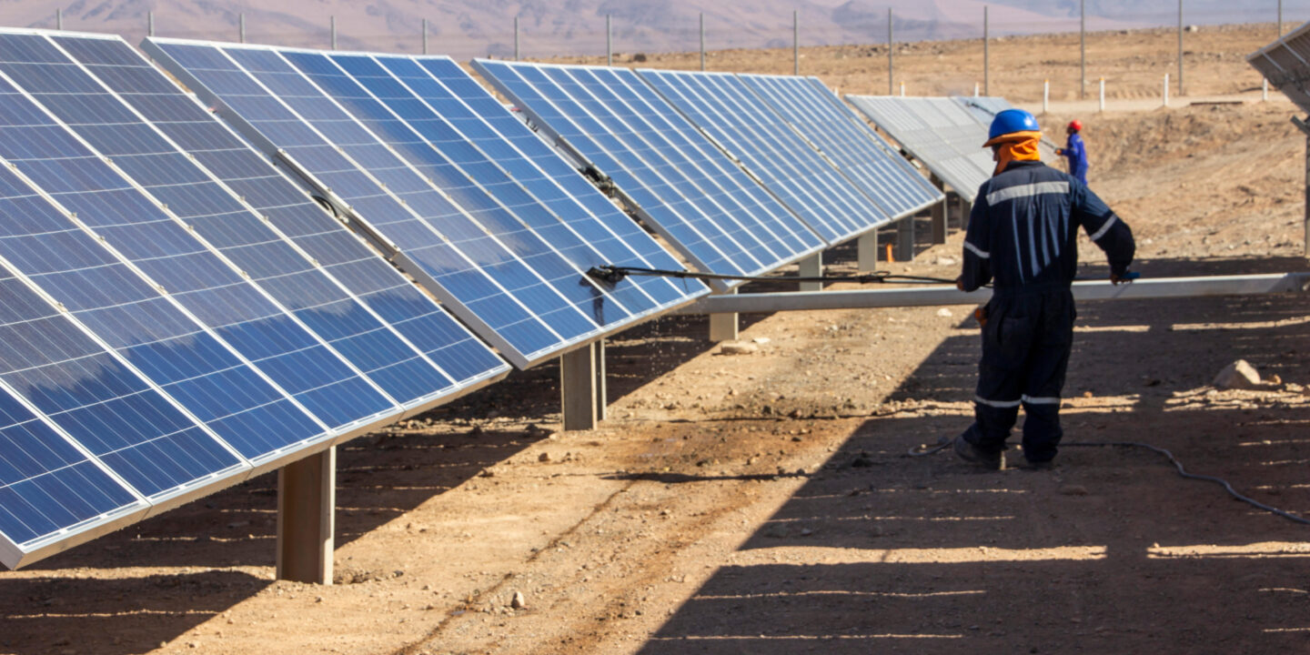 Un trabajador limpia paneles solares en el desierto de Atacama, Chile