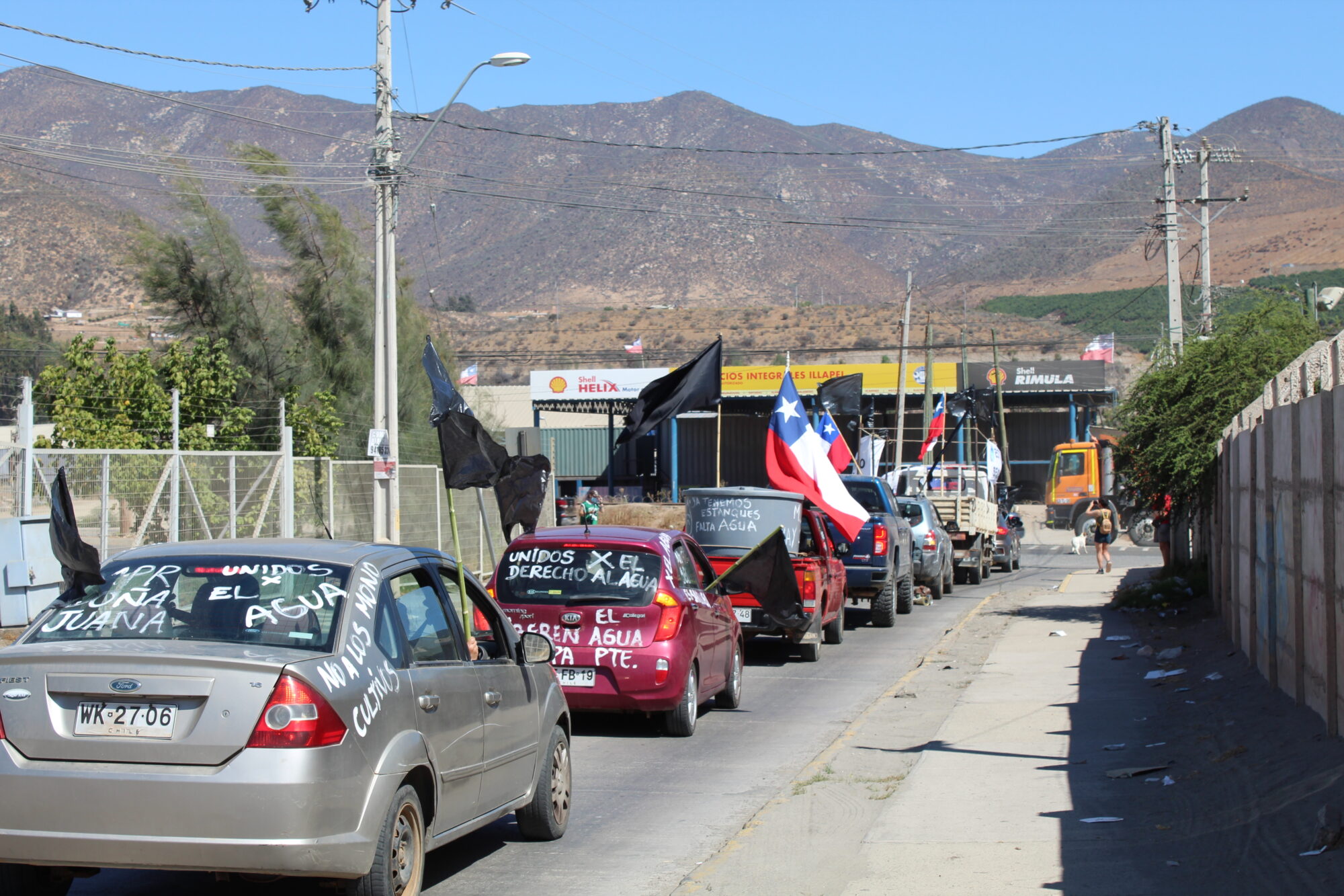 fila de autos con inscripciones en contra de la minería y banderas de chile