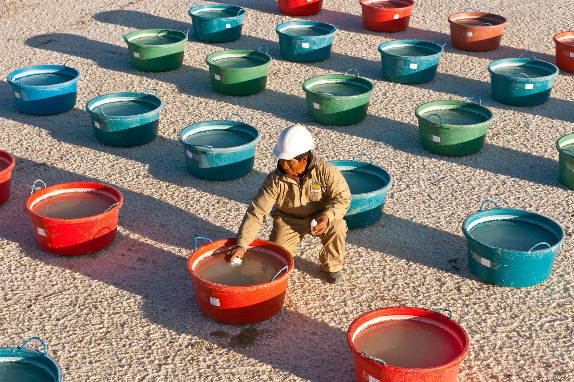 Person in work clothes and rows of coloured containers