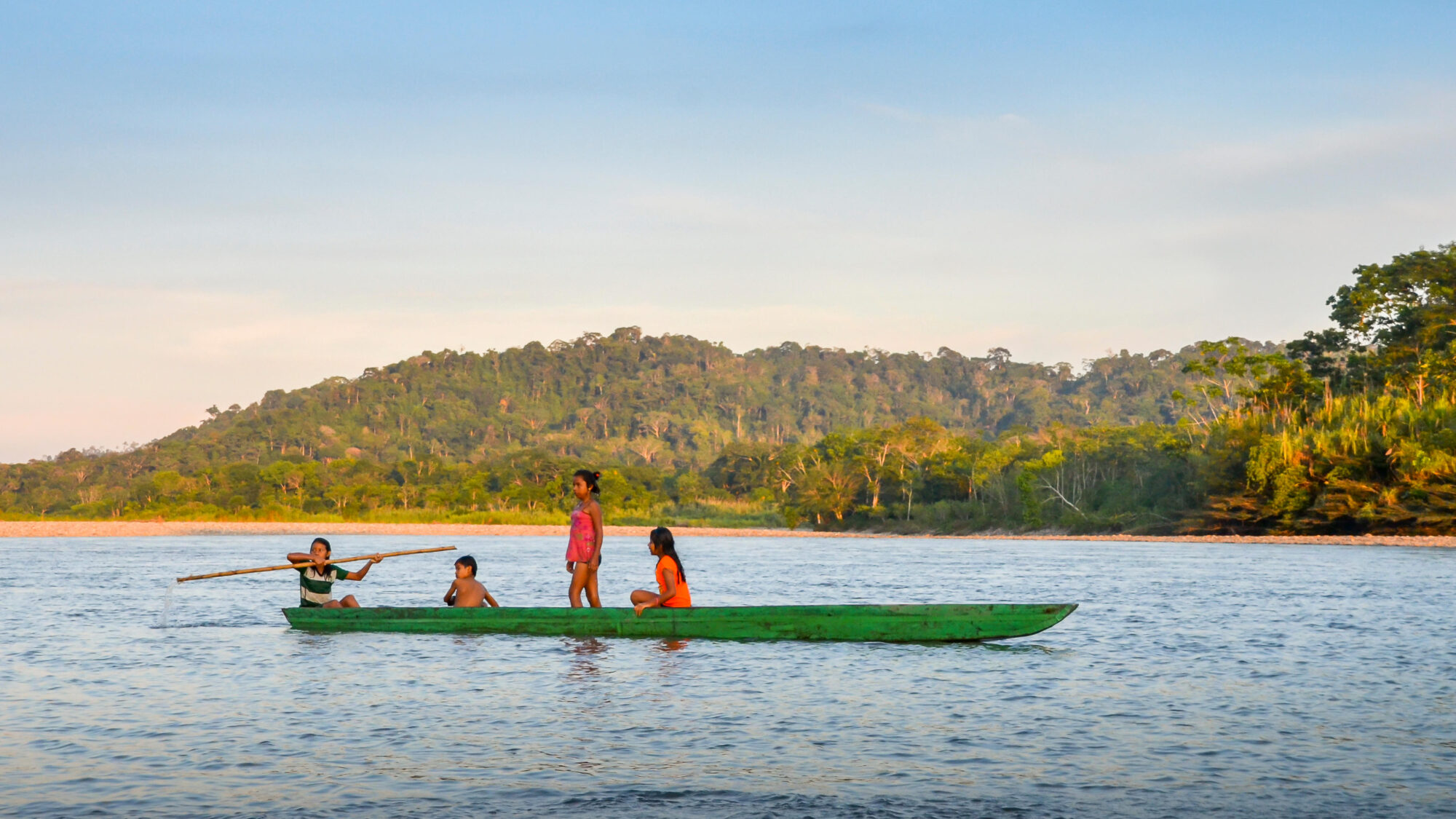cuatro niños una canoa verde en el río Napo