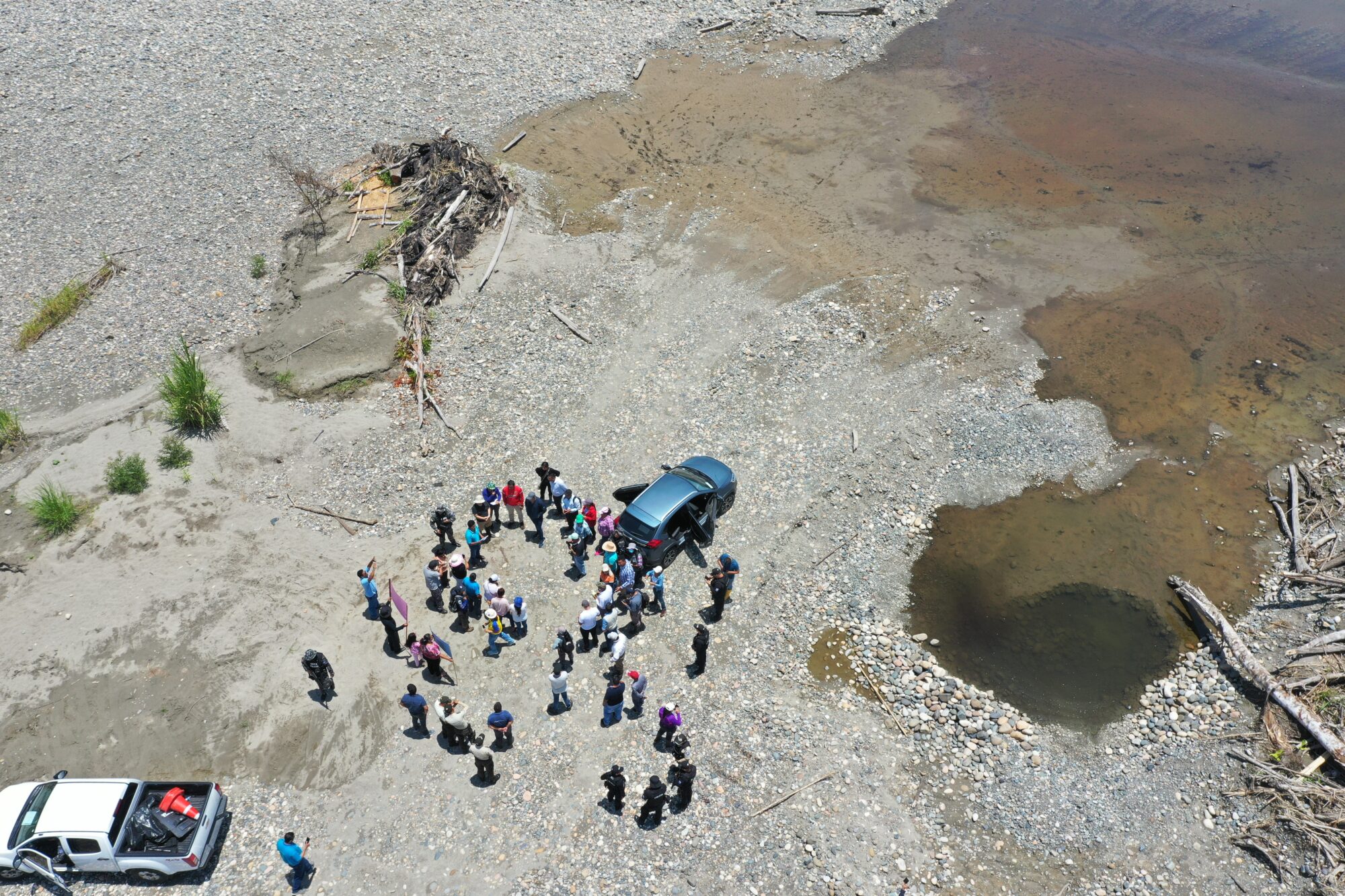 aerial view of a group of people and two cars near a river