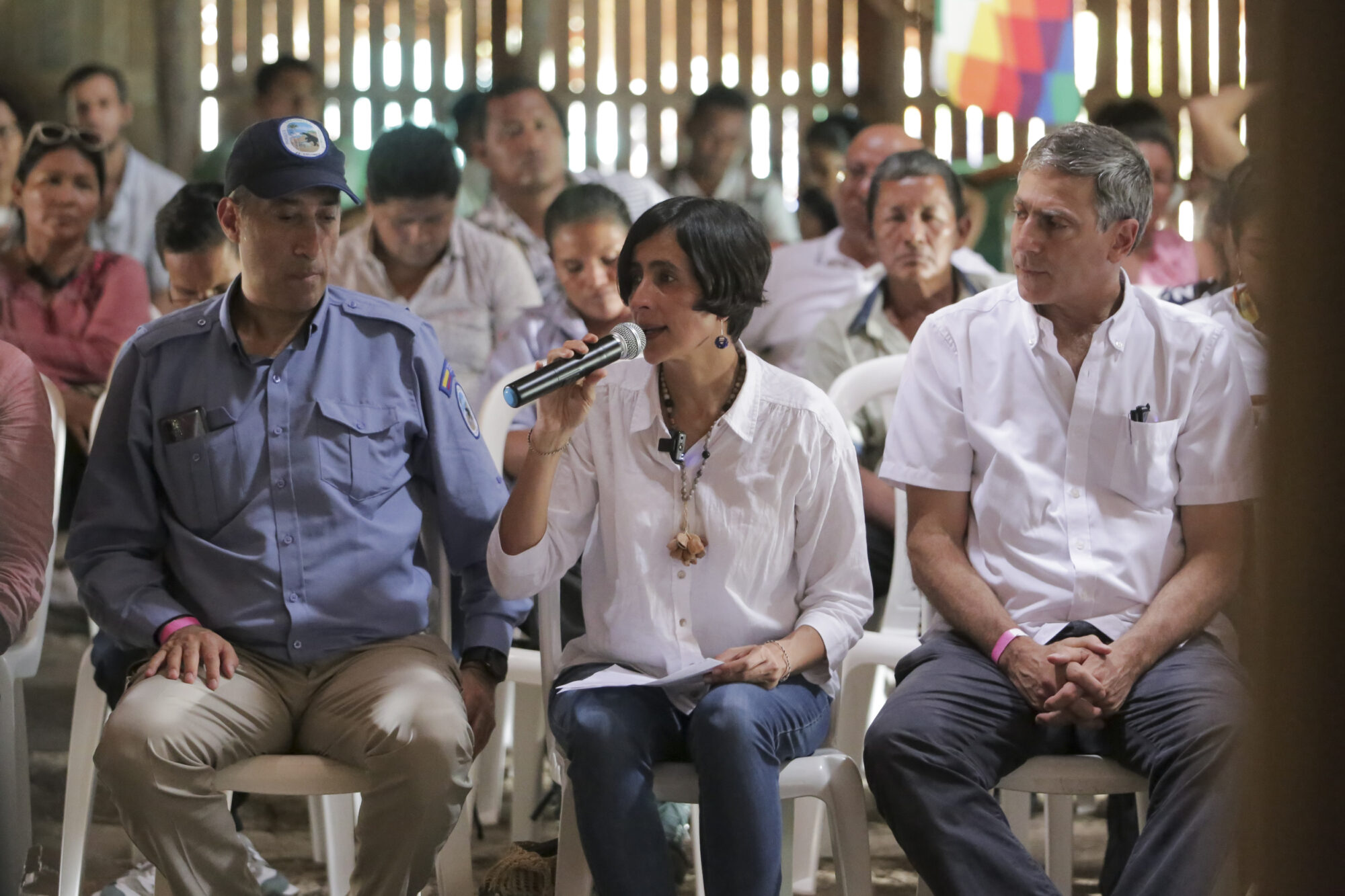 Susana Muhamad con un micrófono en su mano, sentada entre un grupo de personas