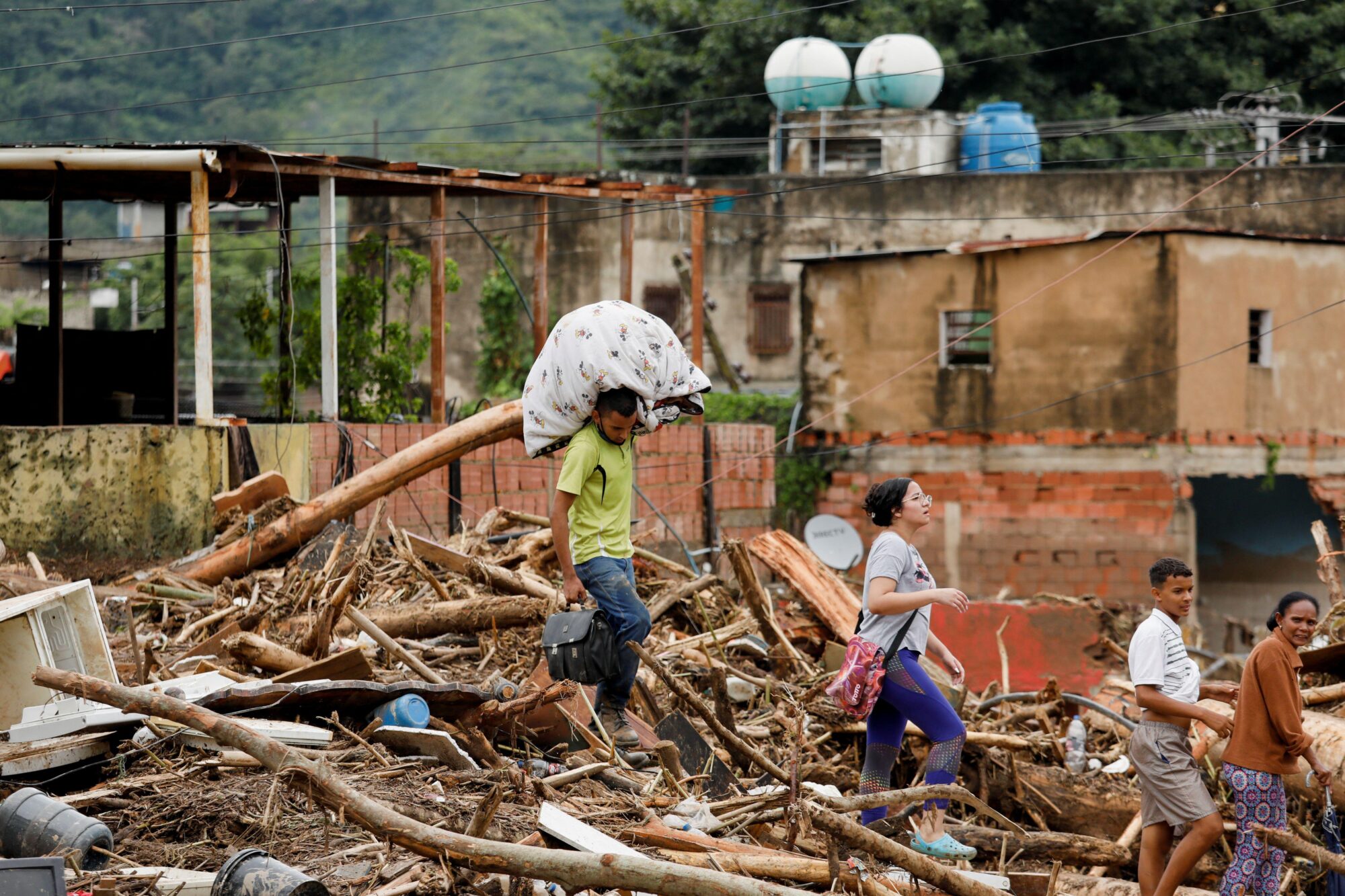 People carry belongings through damage after floods in Venezuela in October 2022