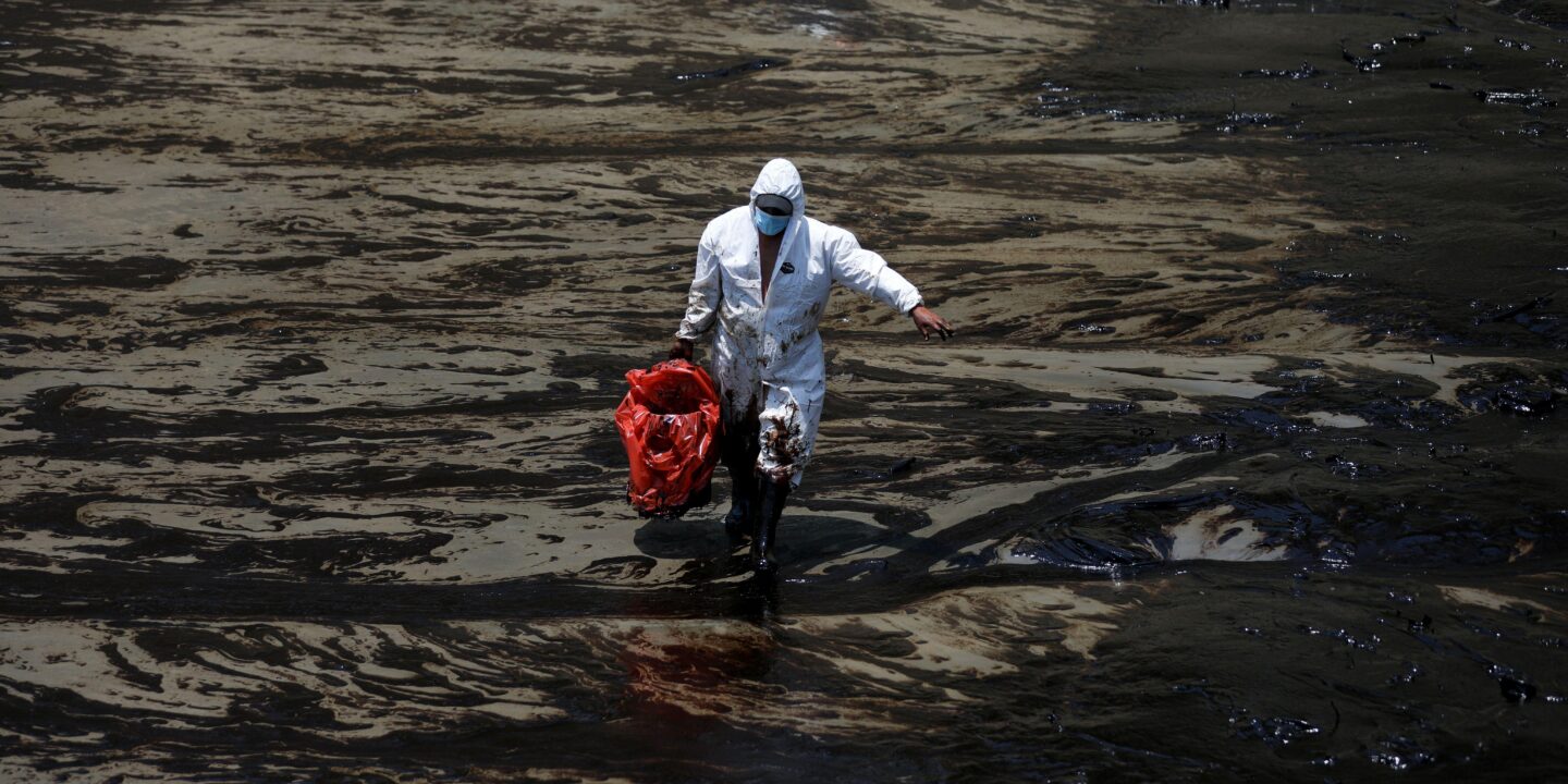<p>Un trabajador limpia una playa en Ventanilla, Perú, tres días después de que miles de barriles de petróleo se derramaran de una refinería propiedad de la empresa española Repsol en enero de 2022 (Imagen: Pilar Olivares / Alamy)</p>
