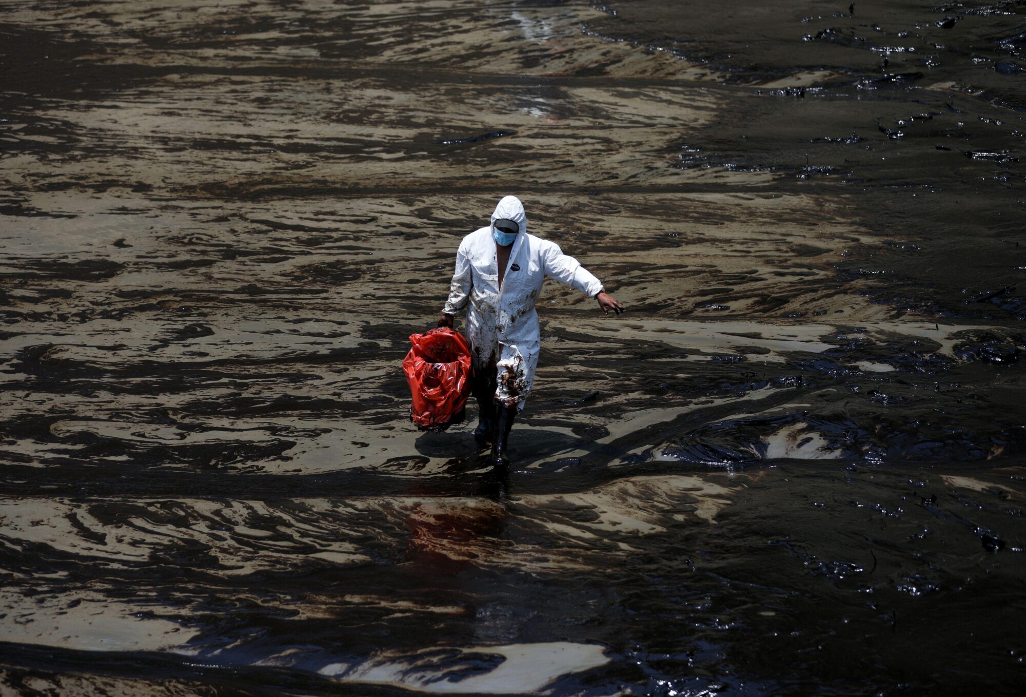 Trabalhador limpa praia em Ventanilla, no Peru, três dias após o vazamento de milhares de barris de petróleo de uma refinaria da empresa espanhola Repsol, em janeiro de 2022 (Imagem: Pilar Olivares / Alamy)
