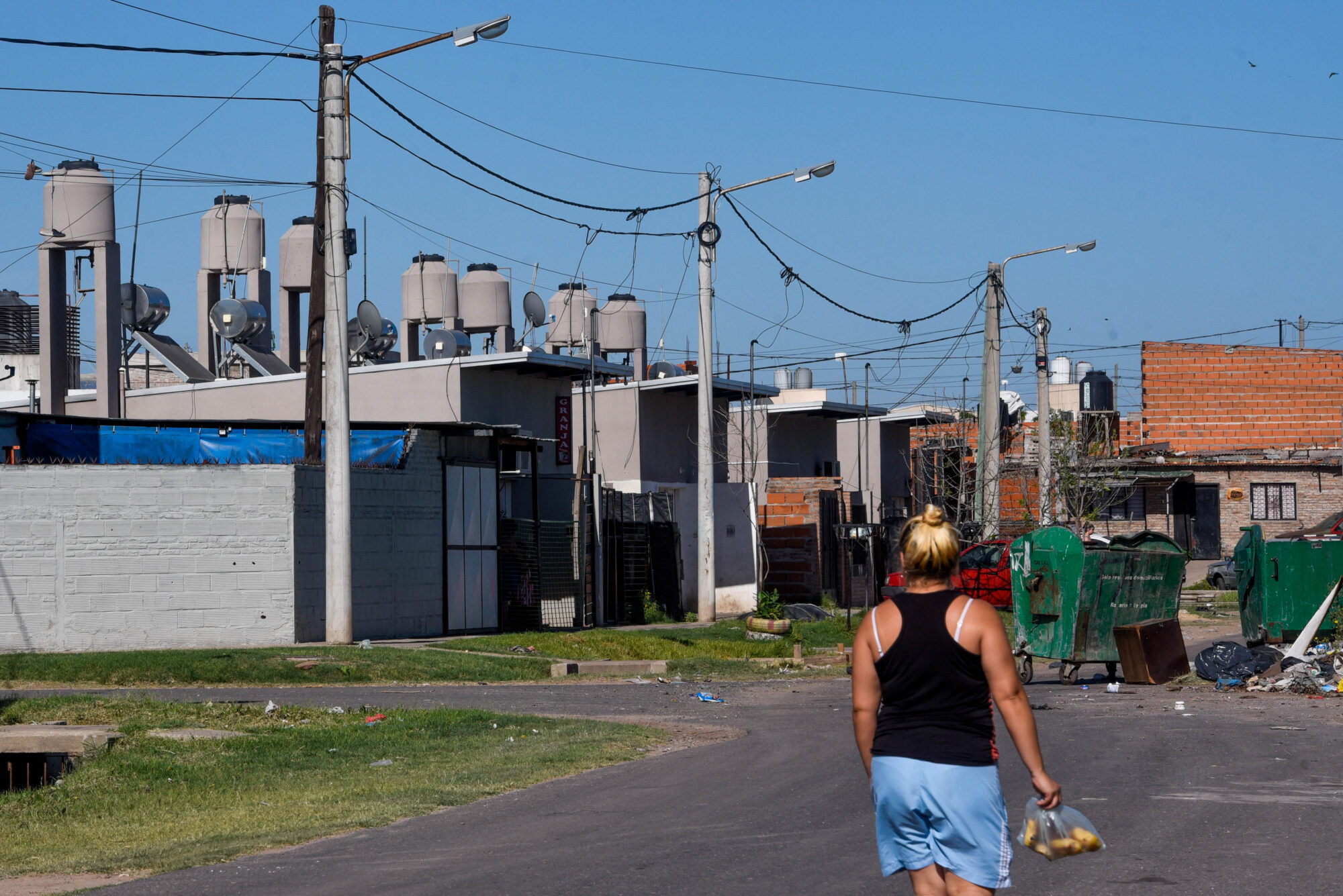 A woman walks in the Godoy neighbourhood of Rosario, Argentina. Rooftop solar collectors on a housing project can be seen in the background