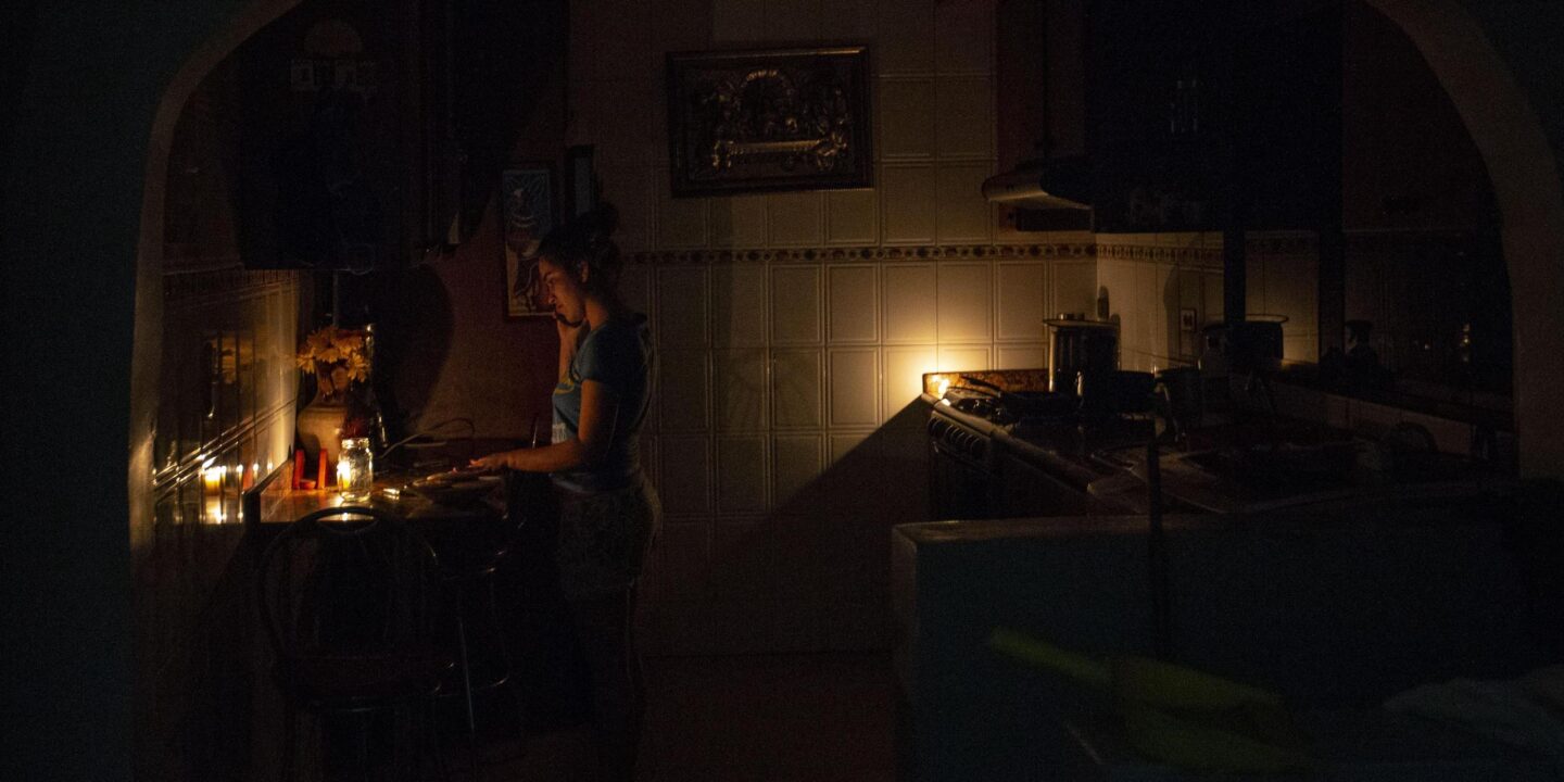 <p>Mulher cozinha à luz de velas em Caracas, na Venezuela, durante apagão em 2020 (Imagem: Jose Isaac Bula Urrutia / Alamy)</p>