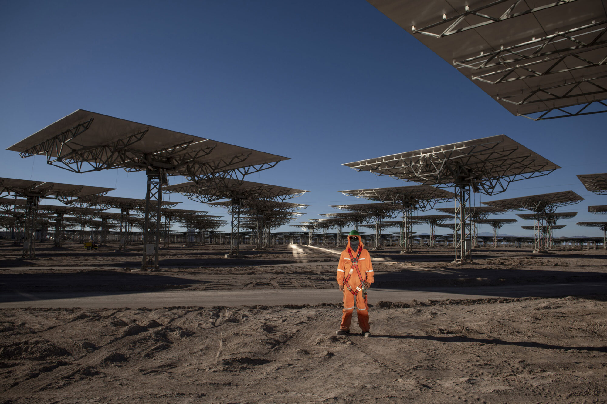 person in orange jumpsuit standing next to heliostats