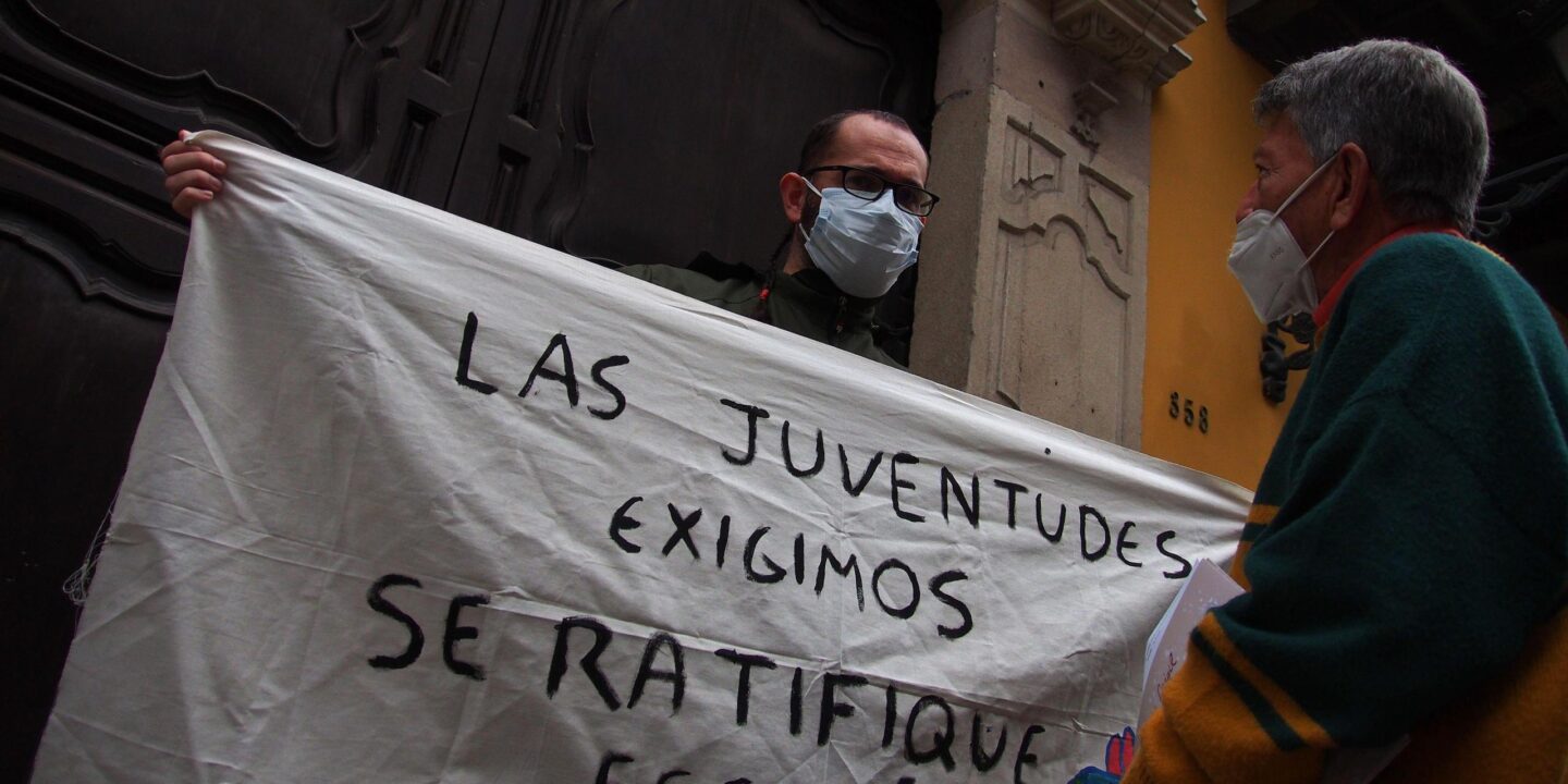 Un activista con una pancarta que dice "Las juventudes exigimos se ratifique Escazú", frente al Ministerio de Relaciones Exteriores de Perú.