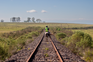 Un hombre andando a caballo por unas vías de tren