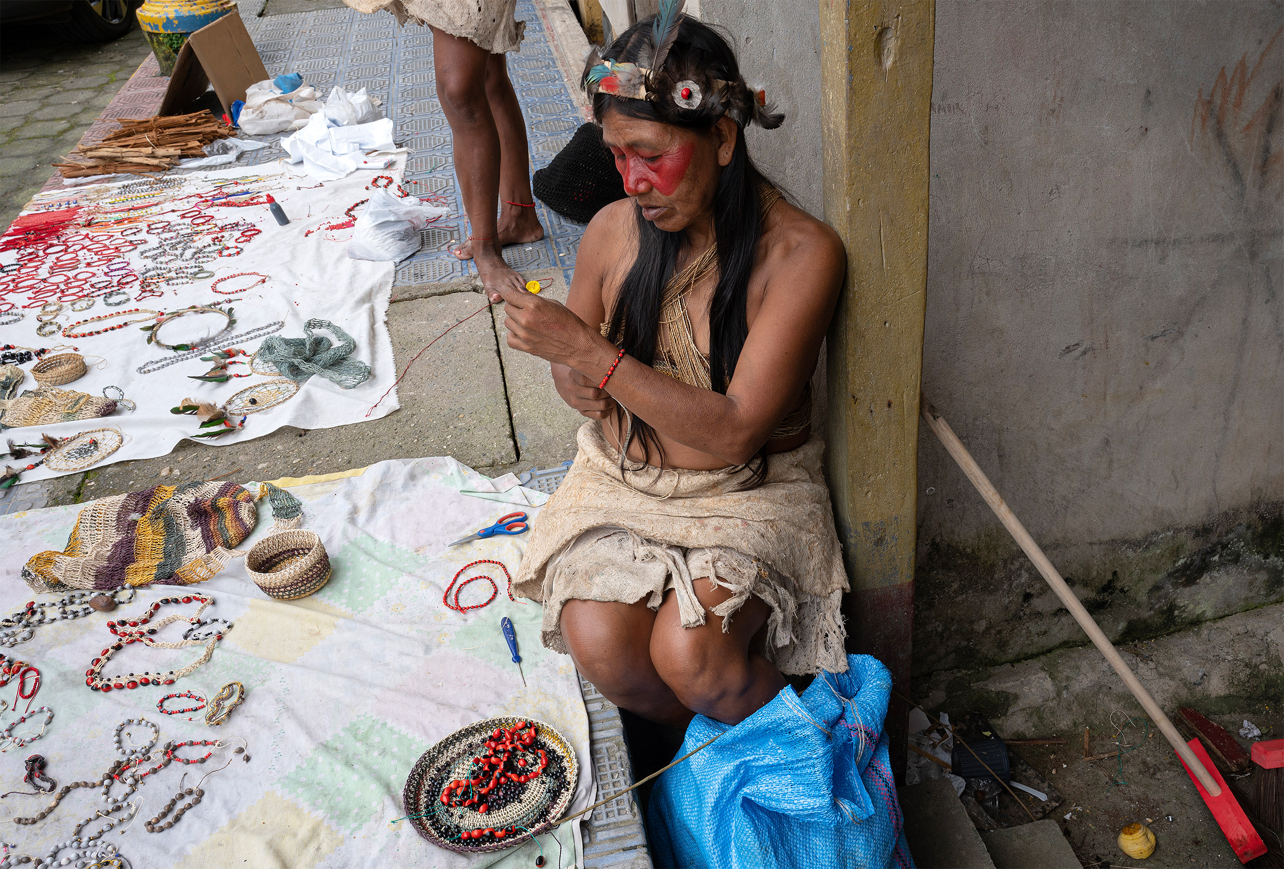 woman on street with display of beaded craft