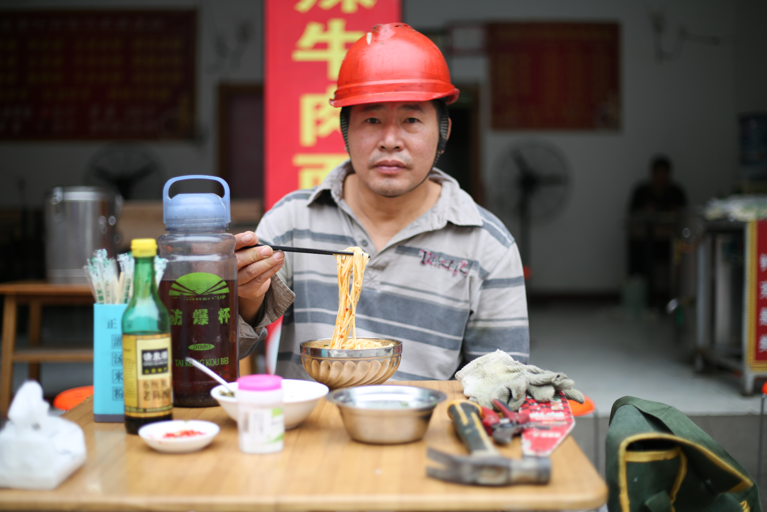 un hombre con un casco rojo comiendo fideos