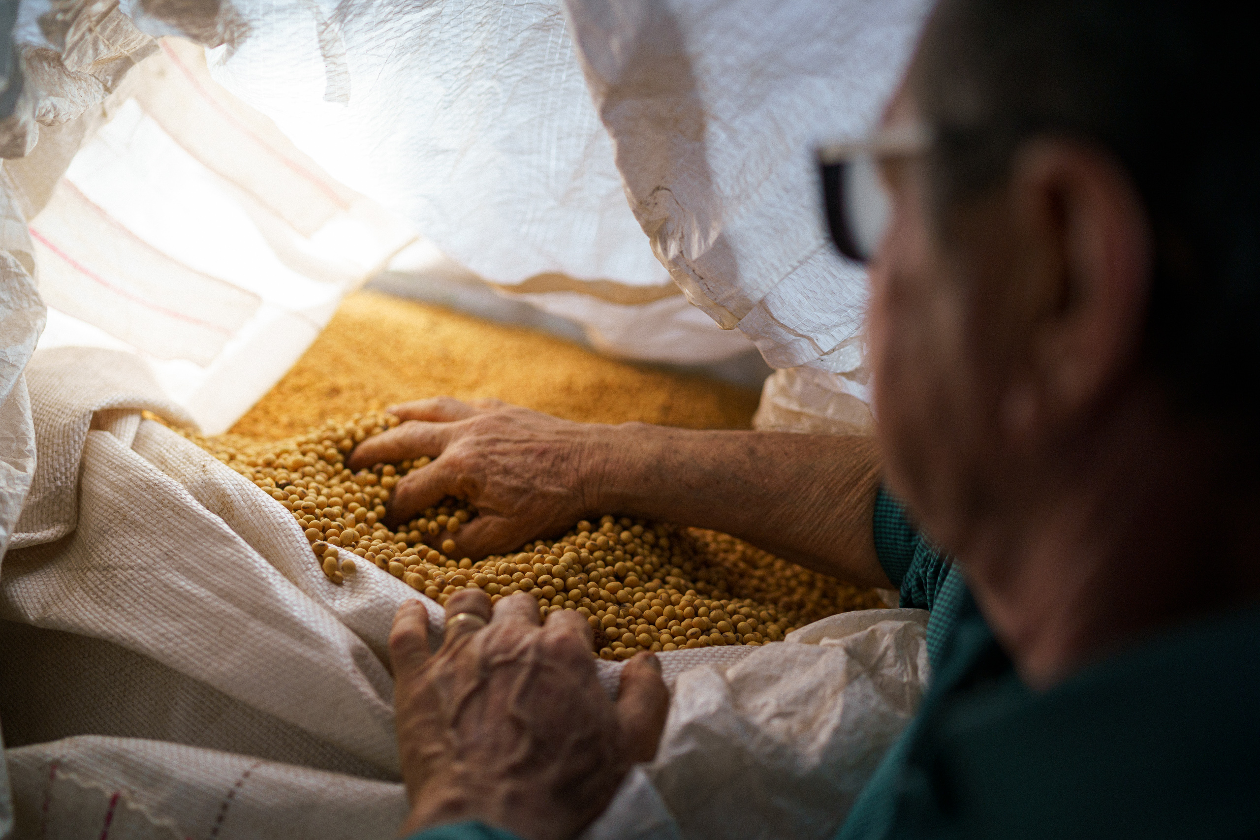 Un hombre abriendo una bolsa de granos de soja