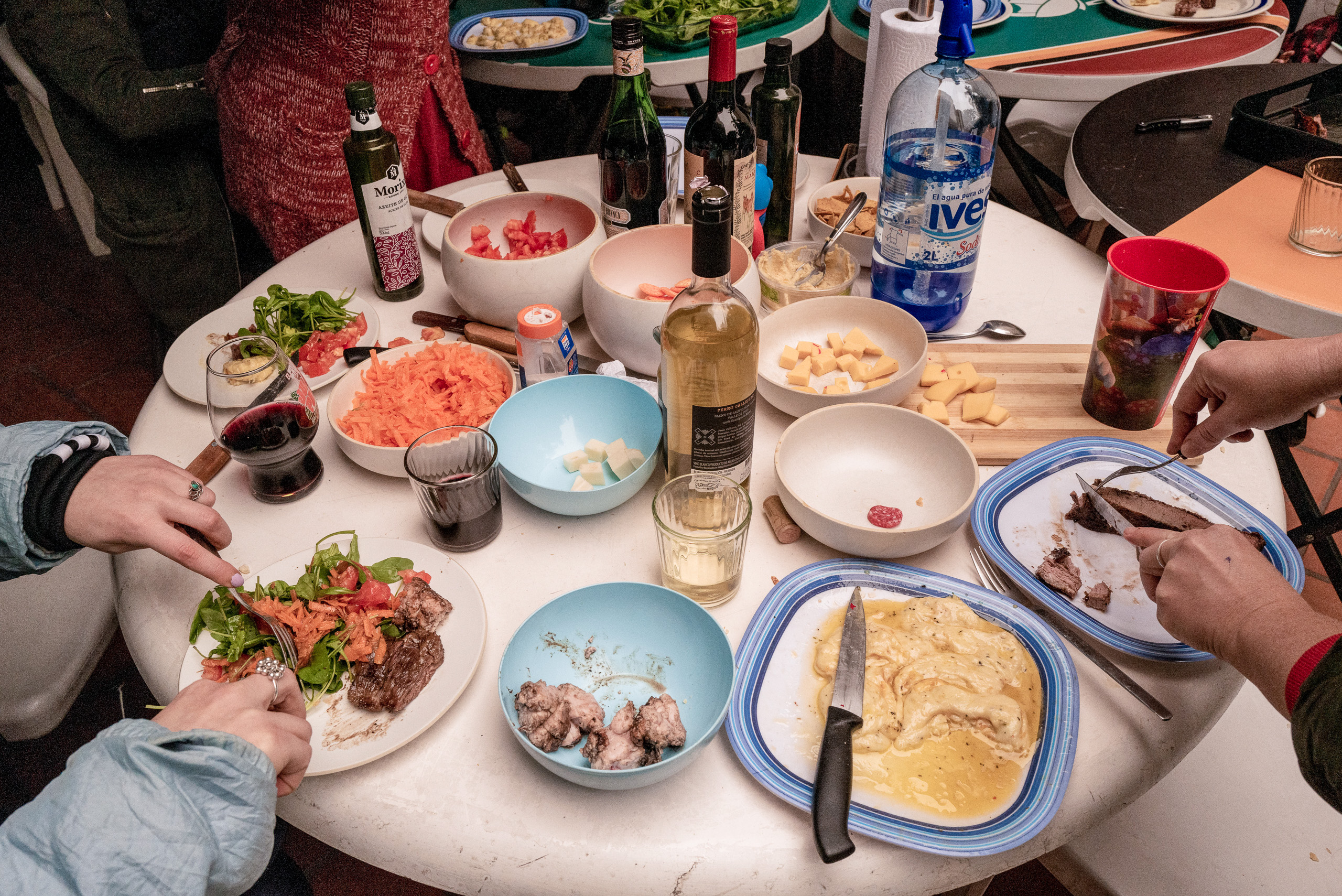 una mesa con diferentes platos con cortes de carne, verduras y bebidas