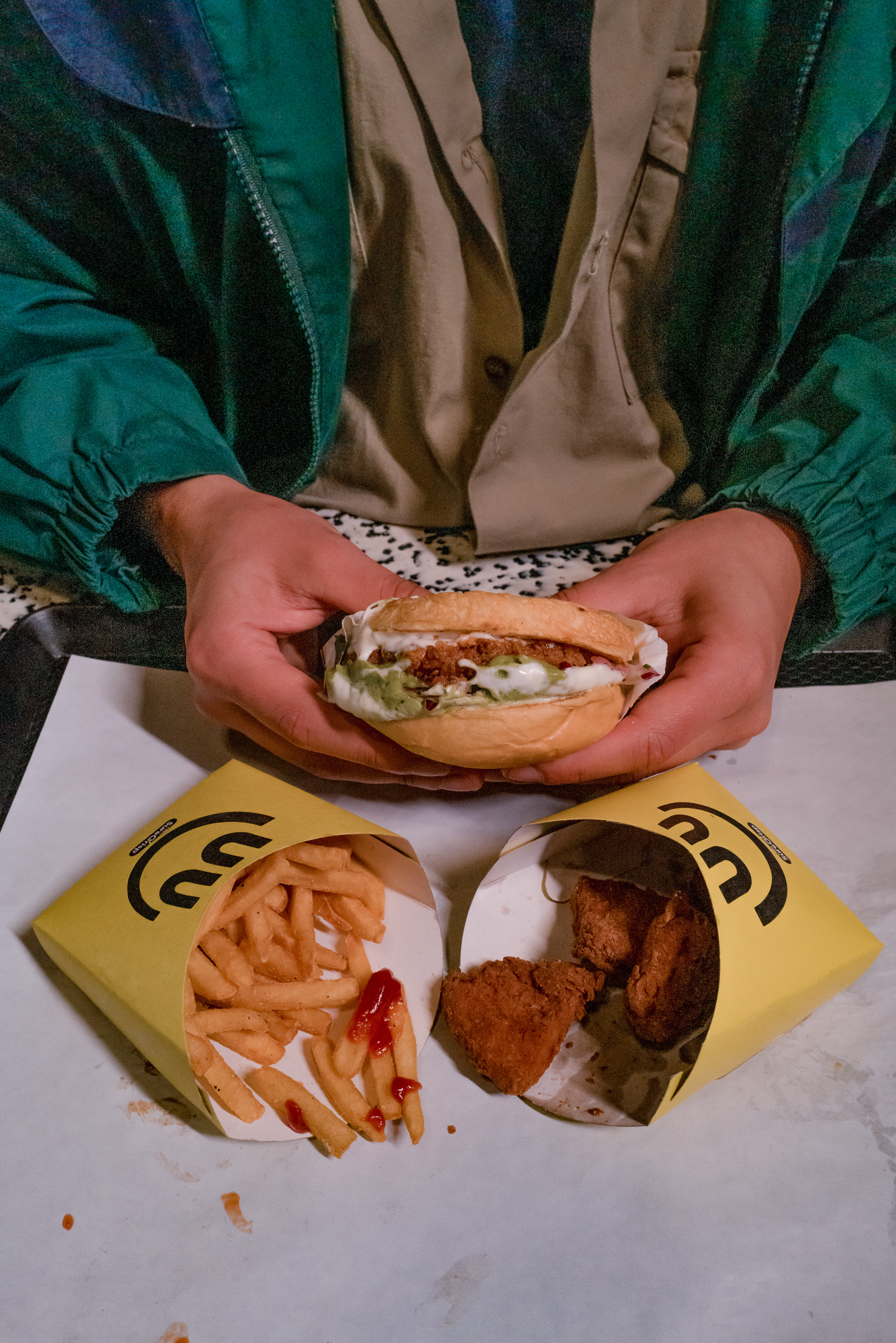 una persona con una hamburguesa con papas fritas en la mesa