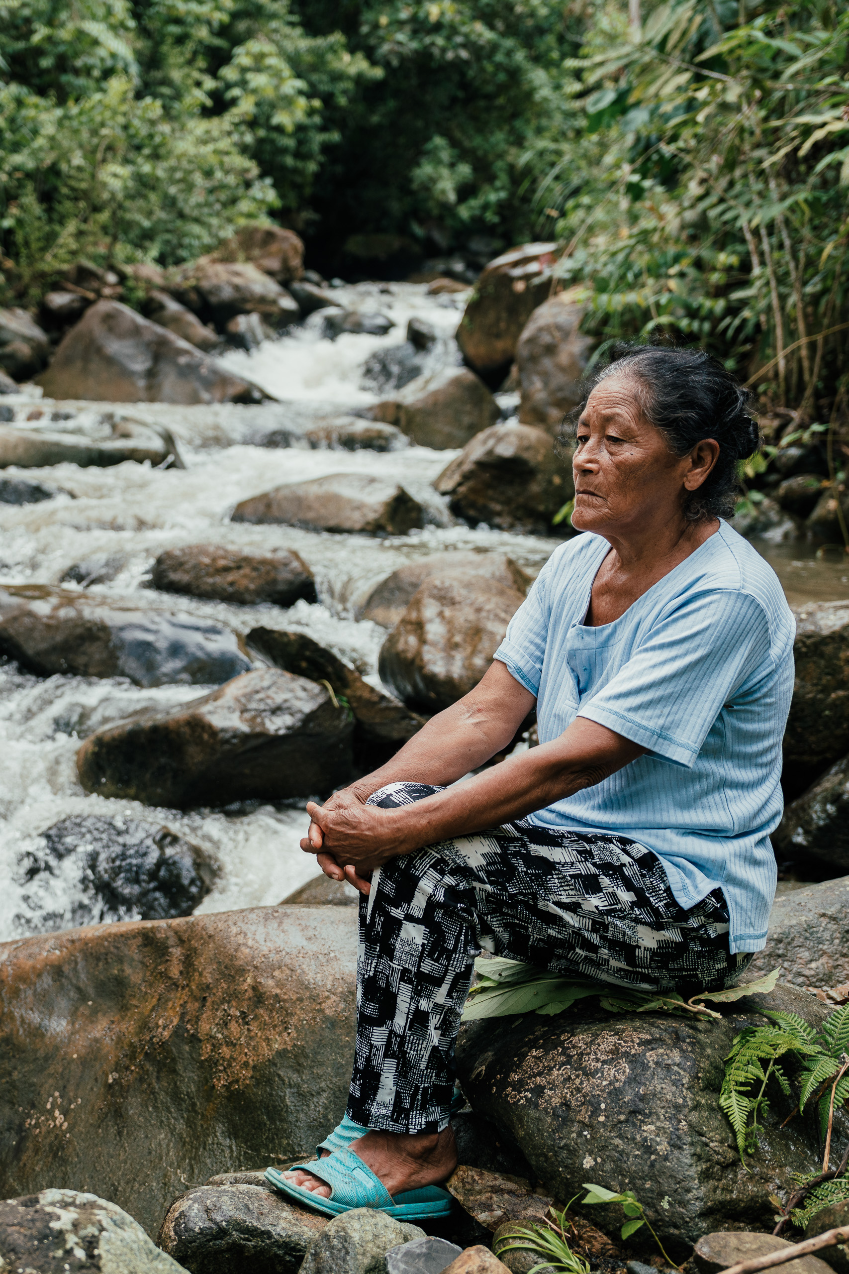 Carmen Guanulema, moradora de San Pablo de Amalí, sentada em um dos canais artificiais da usina hidrelétrica vizinha à sua comunidade