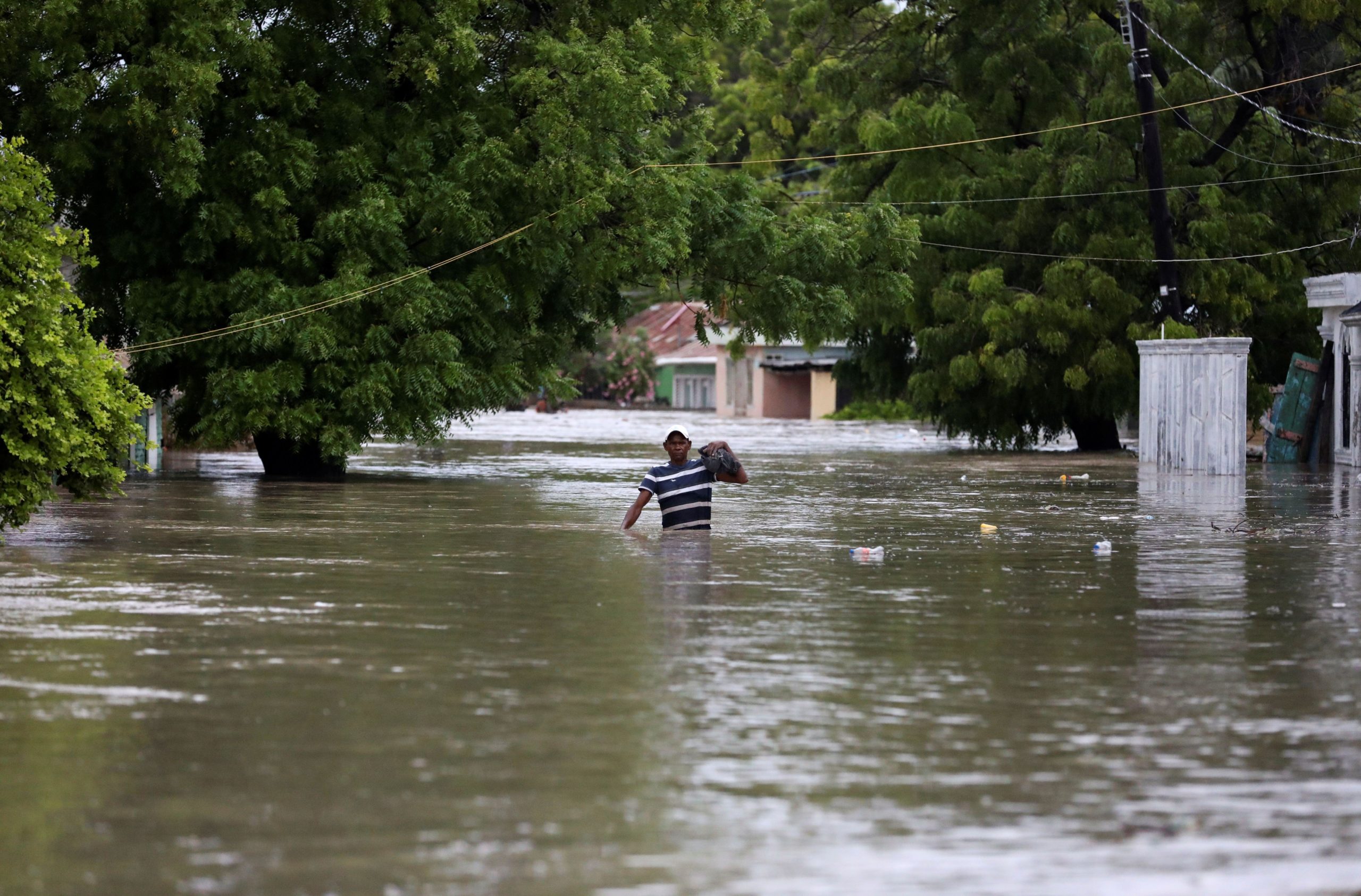 Homem caminha por rua inundada na República Dominicana após a passagem do furacão Laura