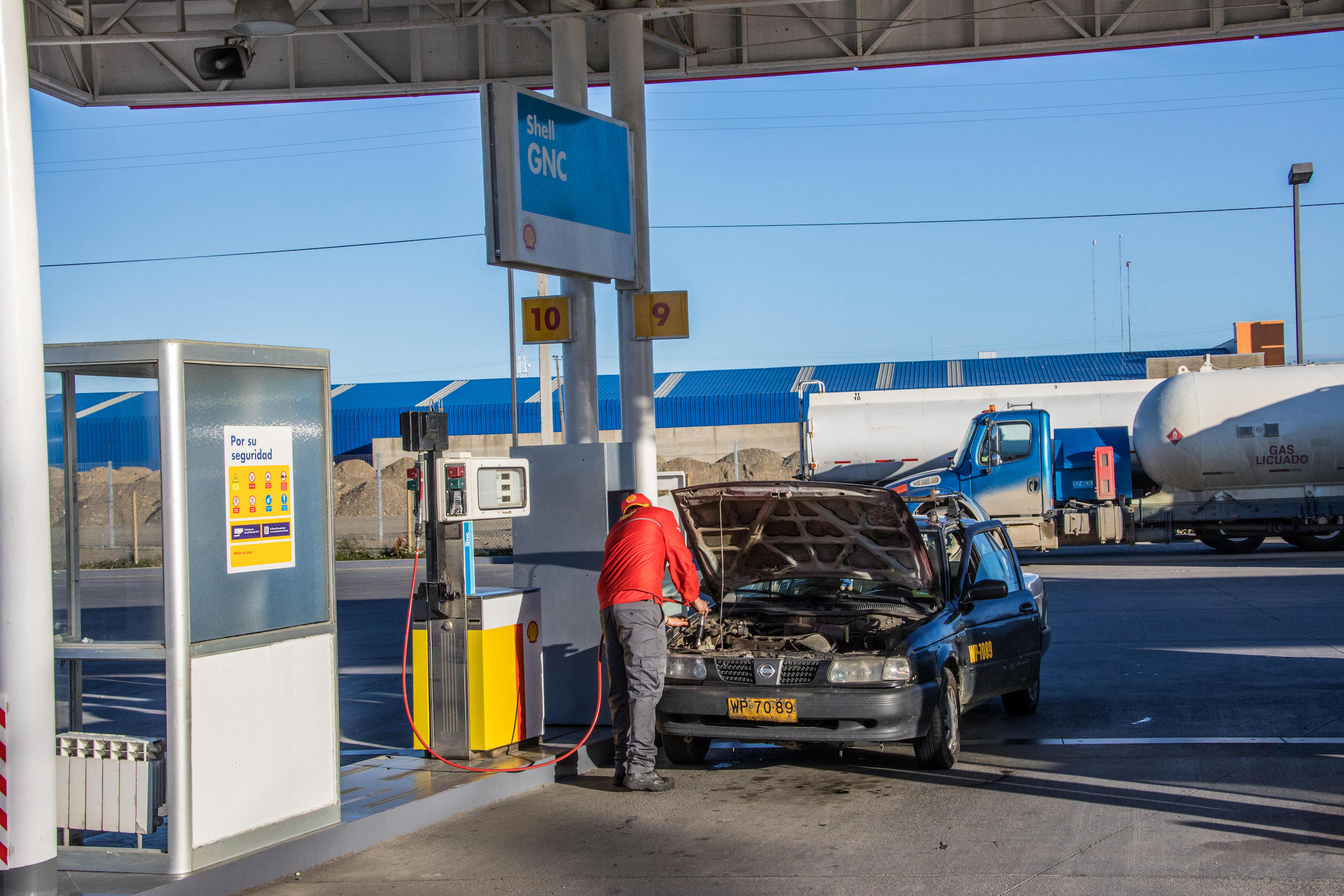 un hombre cargando combustible en un auto