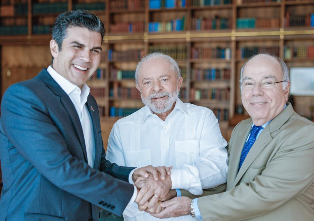 Three men smiling at the camera holding hands in the middle