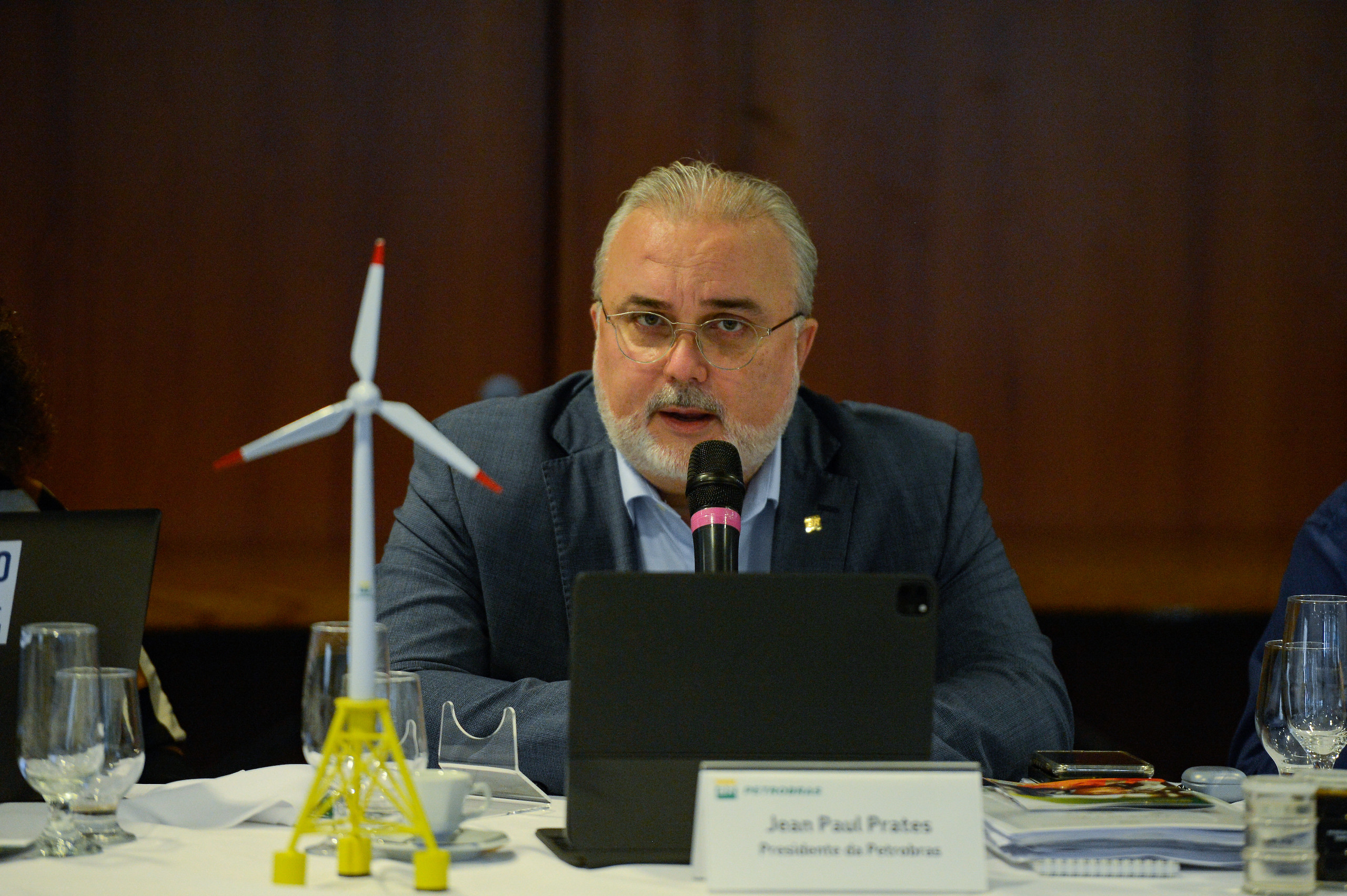 Petrobras CEO Jean Paul Prates speaking into a microphone next to a model wind turbine
