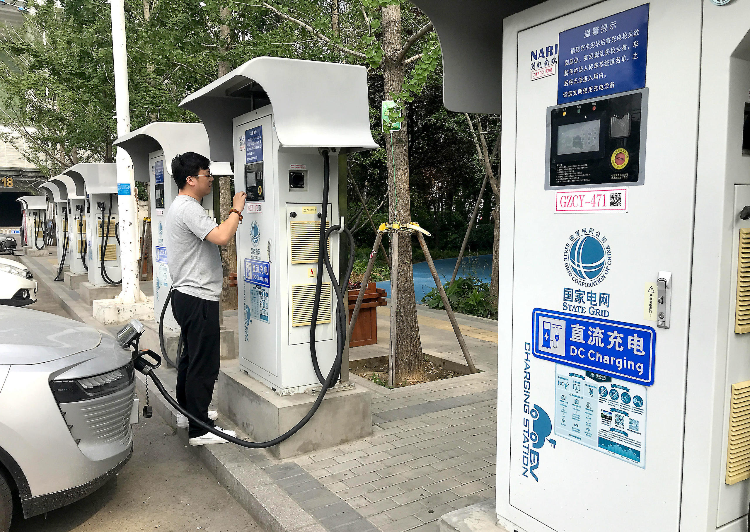 Homem carrega carro elétrico em uma estação em Beijing