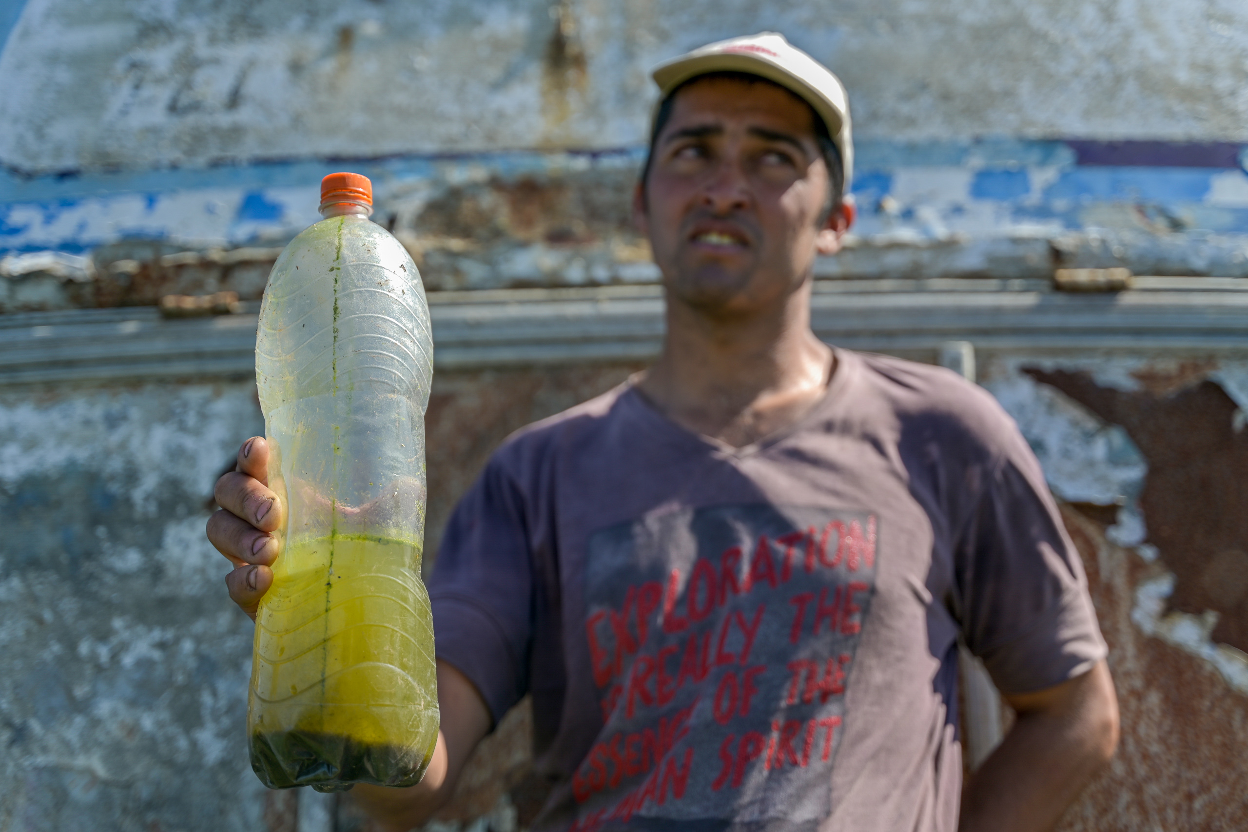 Eduardo Sánchez, pescador da cidade de Arazatí, no Uruguai, segura garrafa d’água repleta de algas
