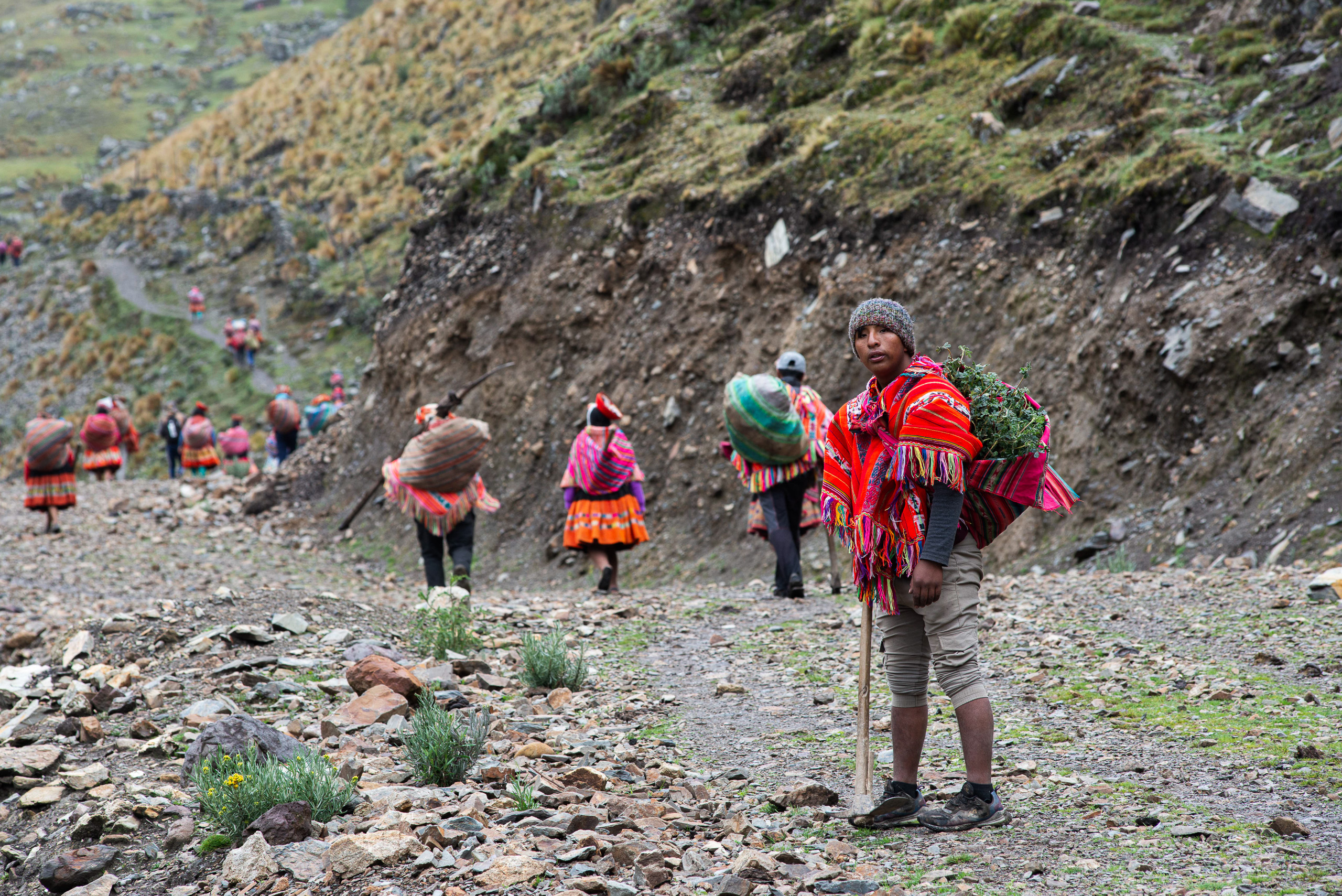 Un grupo de personas en la base de una zona montañosa, vestidas con ropa colorida