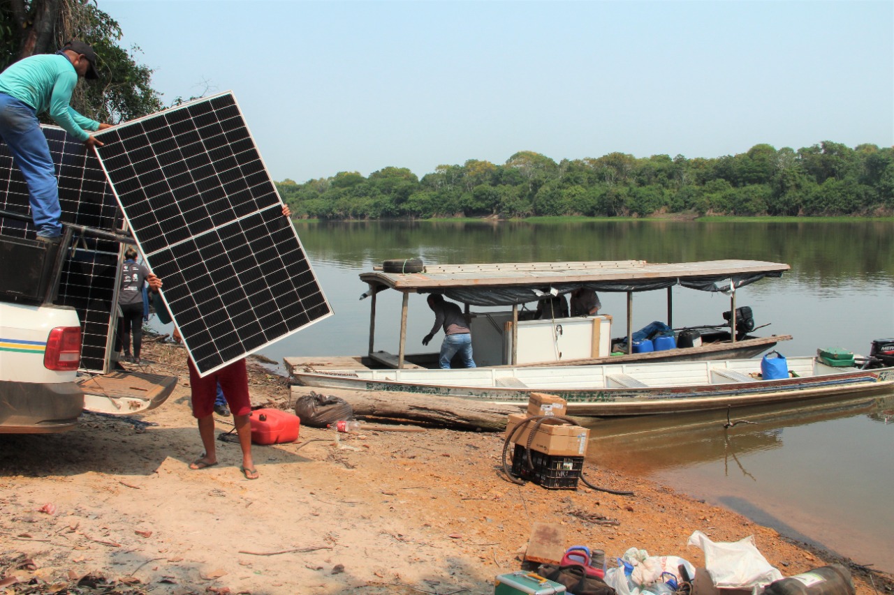 Personas transportando paneles solares desde un barco