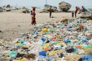 people and boats on highly polluted beach
